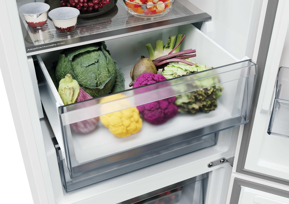 Un cassetto del frigorifero aperto pieno di verdure fresche tra cui cavolo, insalata e cavolfiore.