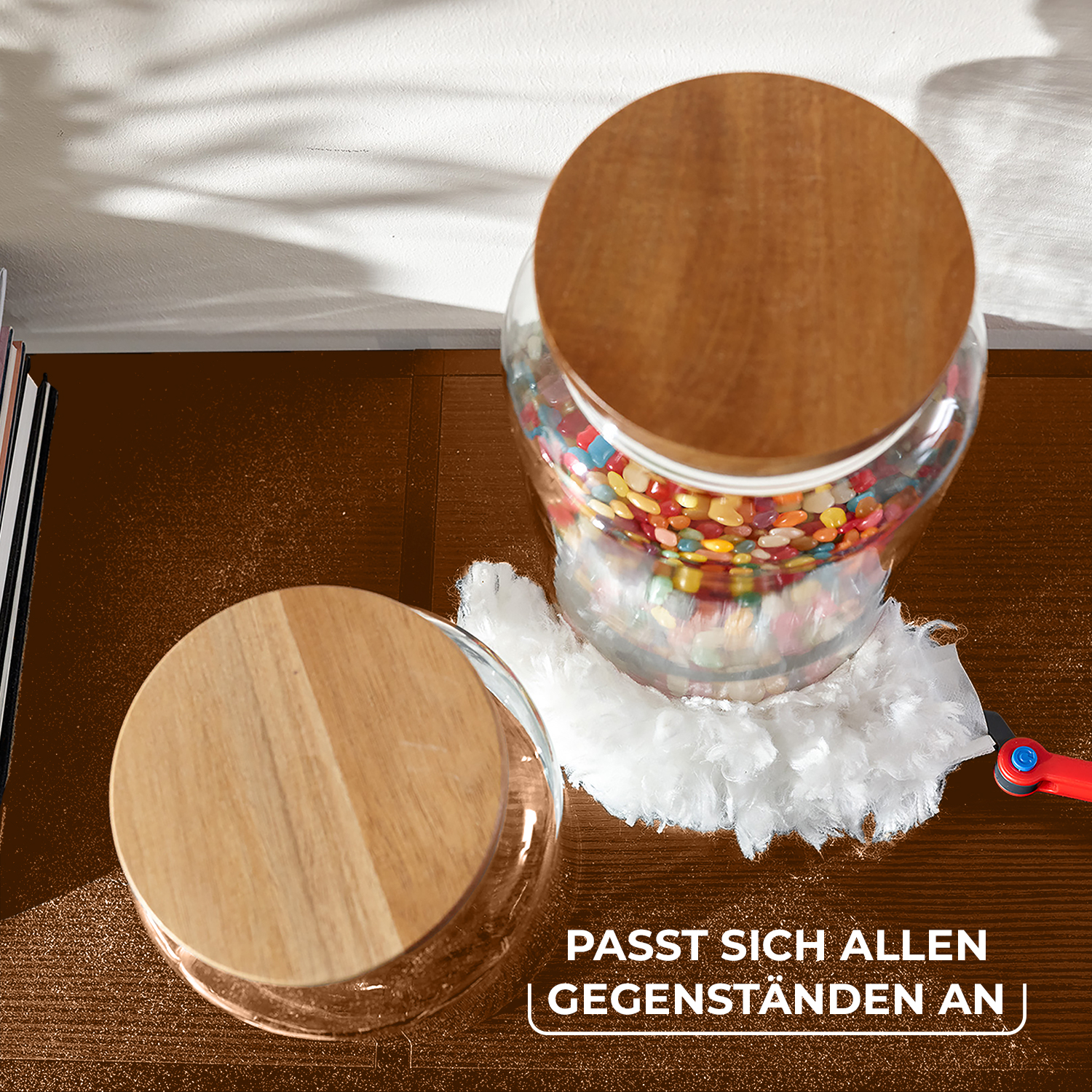 Zwei Glasbehälter mit Holzdeckeln stehen auf einer braunen Oberfläche, einer ist mit bunten Bonbons gefüllt.