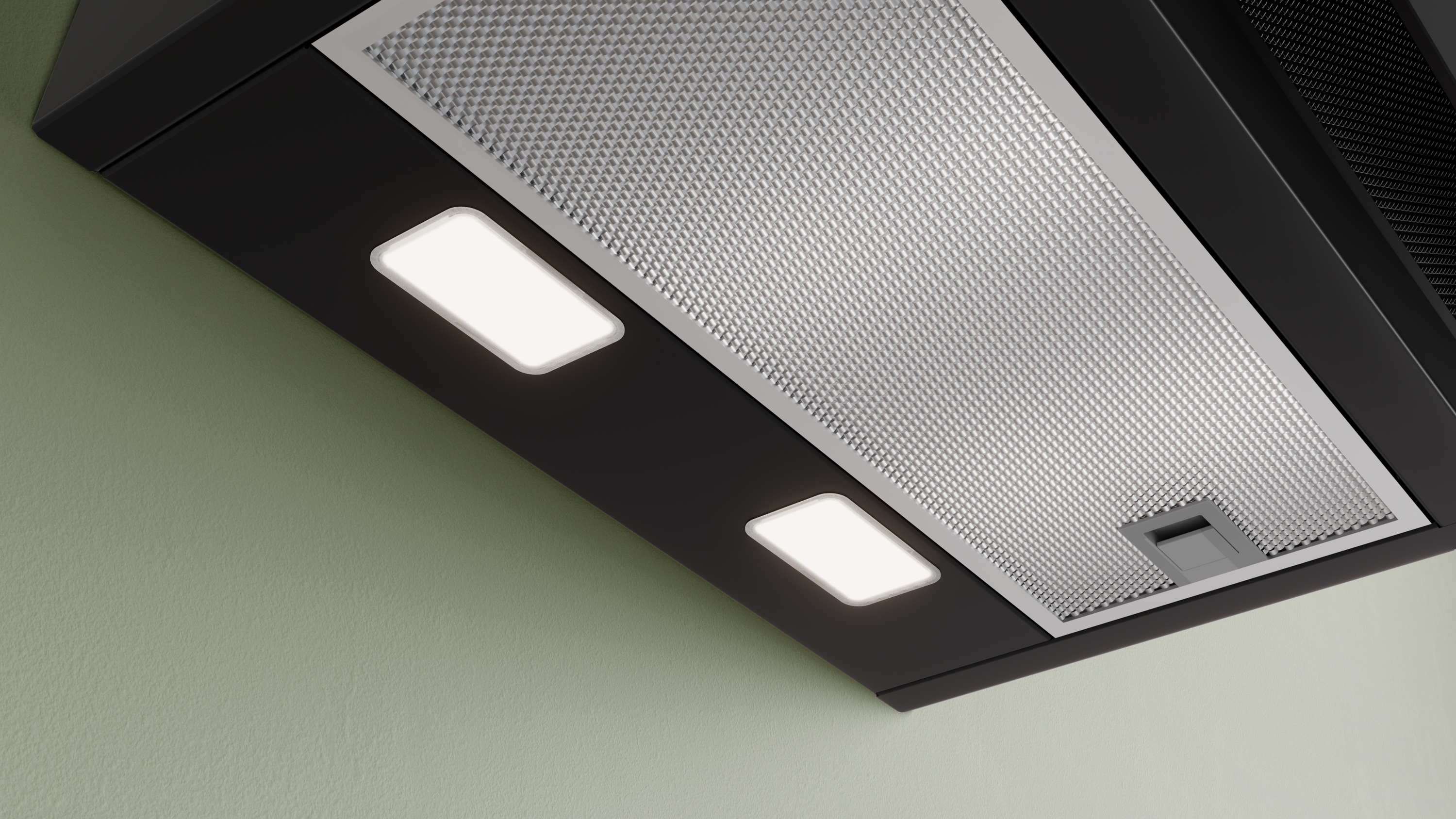 Modern fekete páraelszívó közeli képe fényes LED világítással és fém zsírszűrőkkel egy zöld falon.
