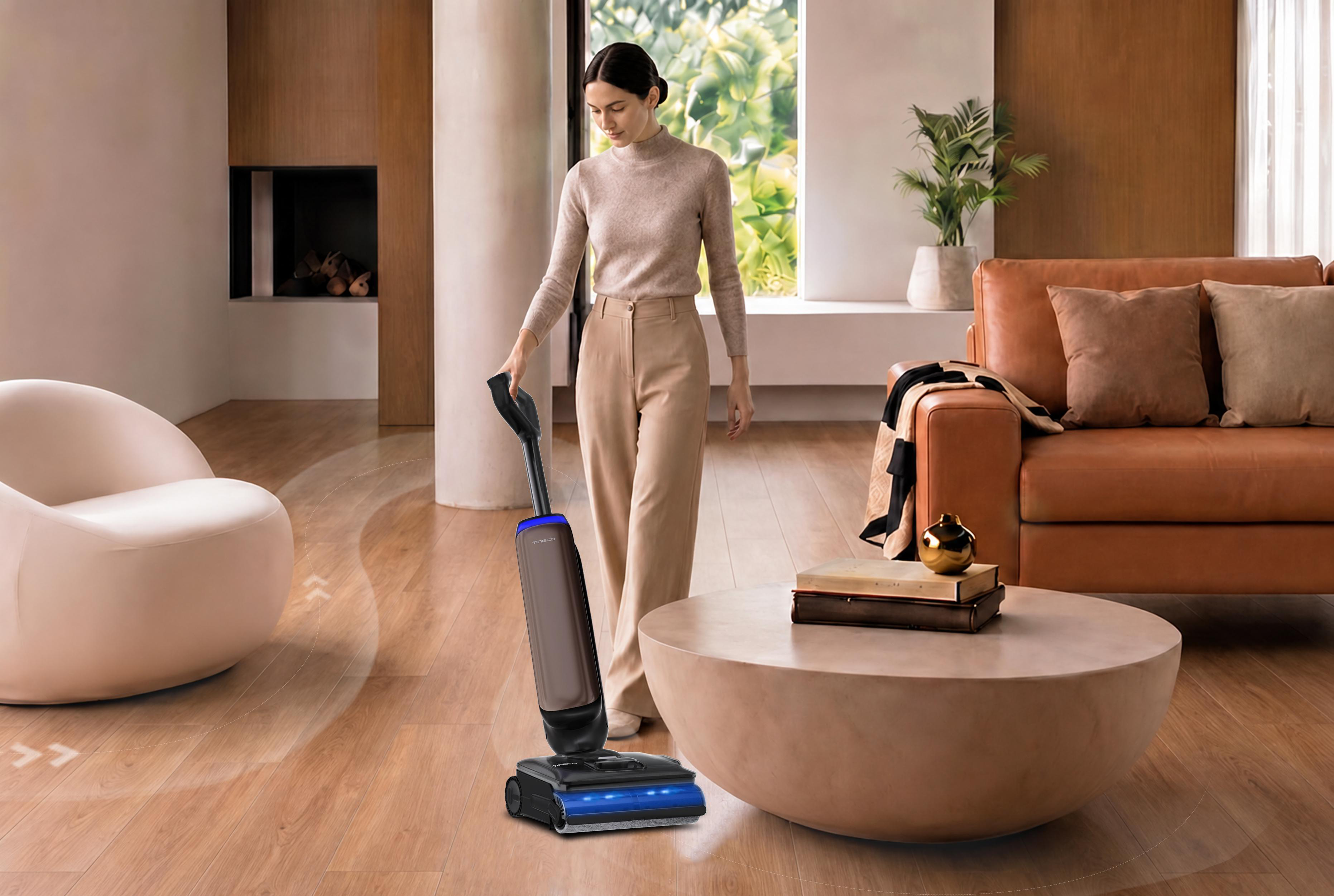Eine Frau in einem modernen Wohnzimmer reinigt den Holzboden mit einem kabellosen Staubsauger.