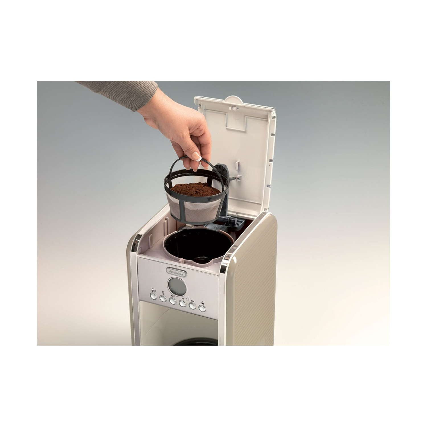 Una mano inserisce un filtro da caffè pieno in una moderna macchina da caffè beige.