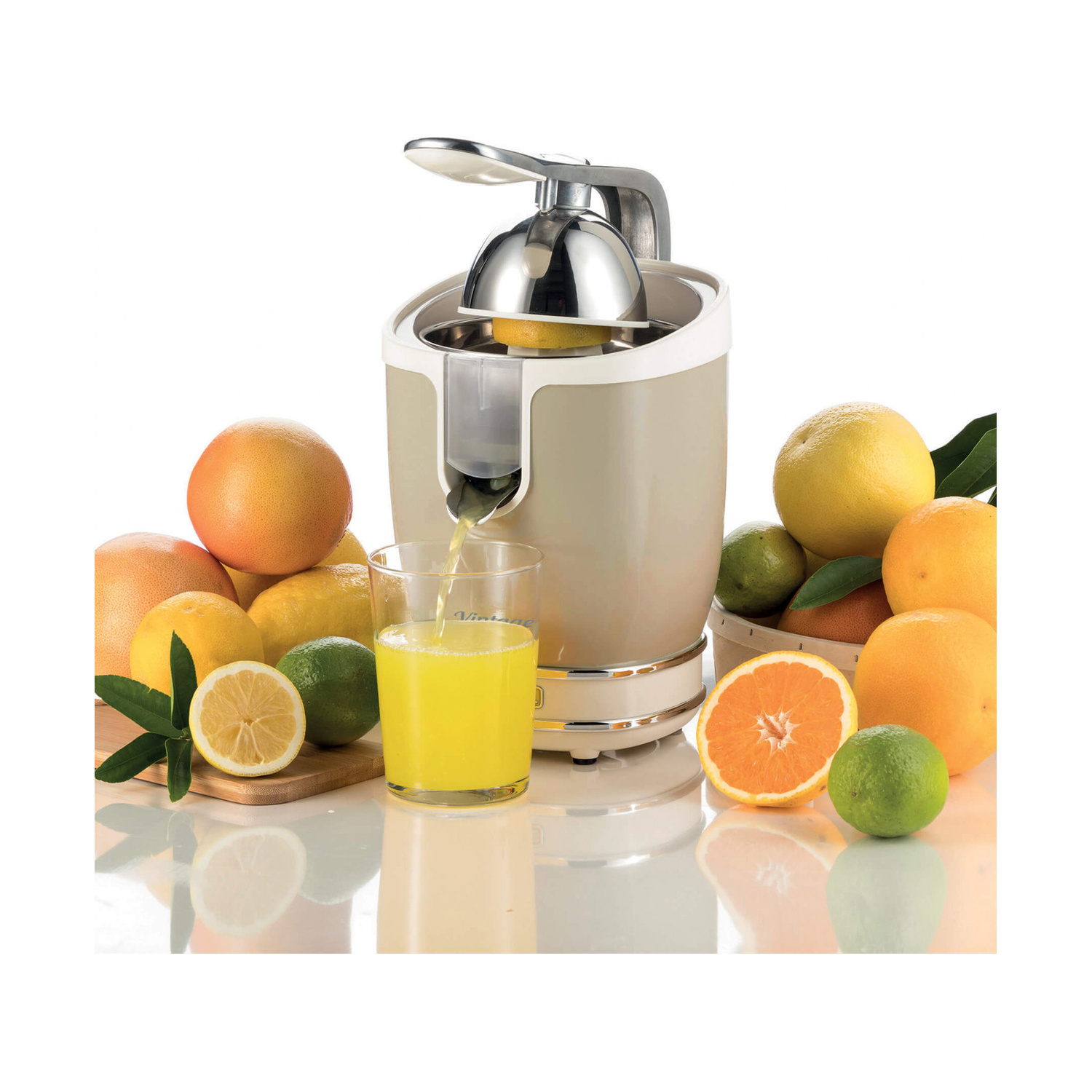 Uno spremiagrumi beige versa succo fresco in un bicchiere, circondato da limoni, arance e lime.