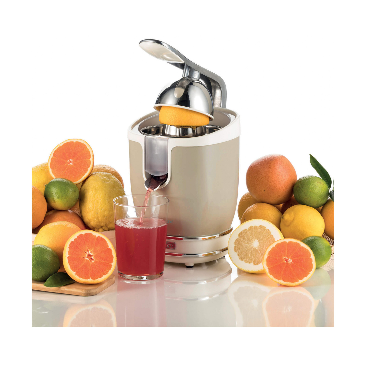 Uno spremiagrumi elettrico versa succo fresco in un bicchiere, circondato da arance, limoni e lime.