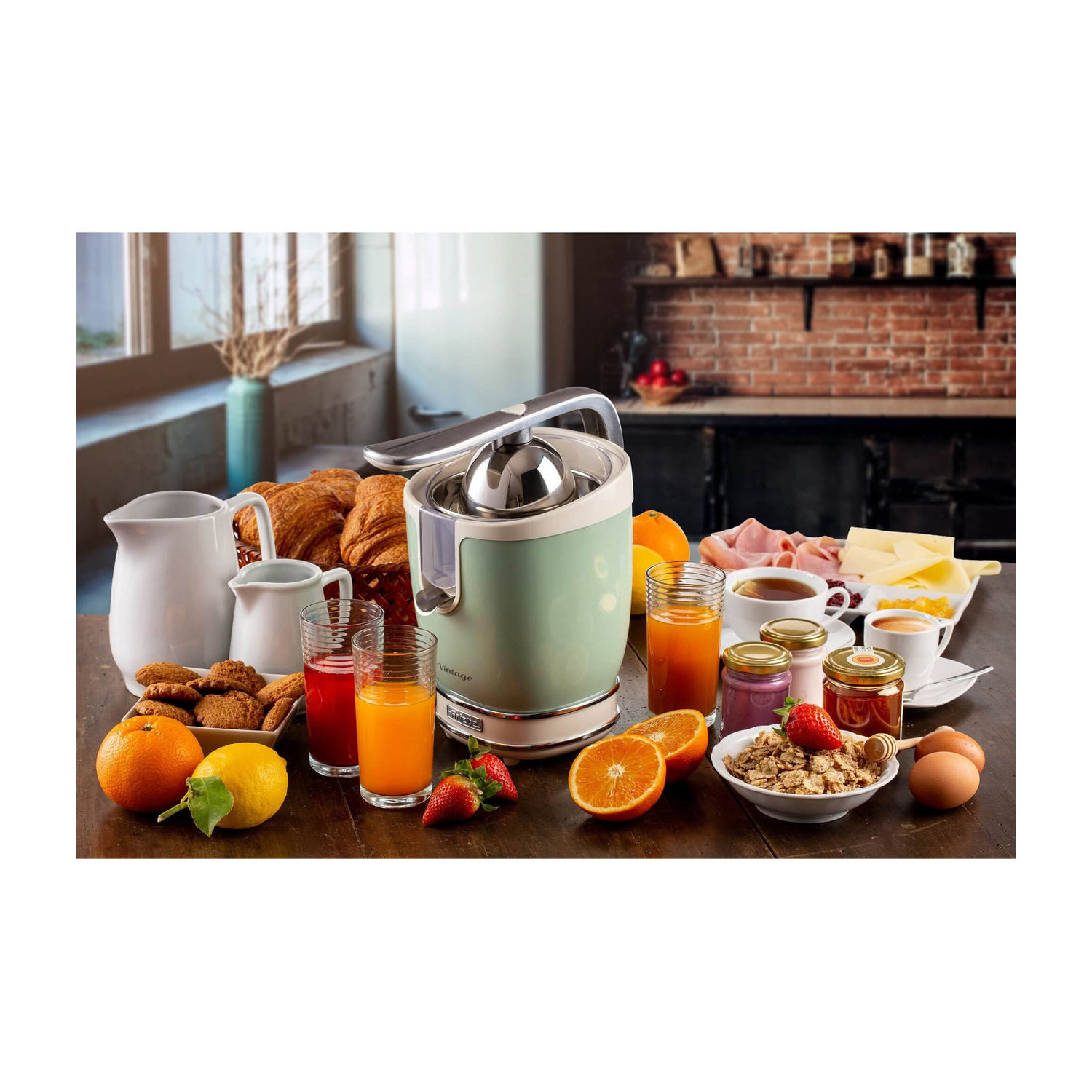 Un tavolo da colazione con spremiagrumi verde menta, croissant, succhi, frutta, cereali e caffè in cucina.