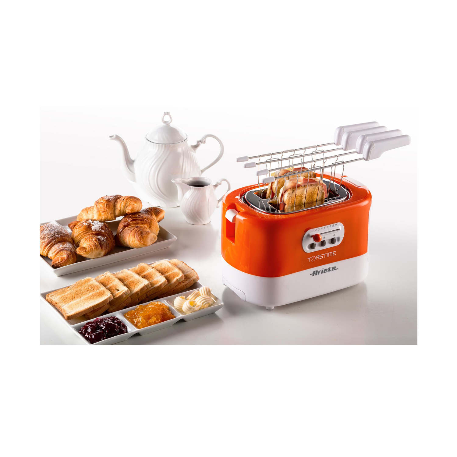 Tapane arancione con panini, croissant, fette biscottate, burro, marmellata, teiera e lattiera.