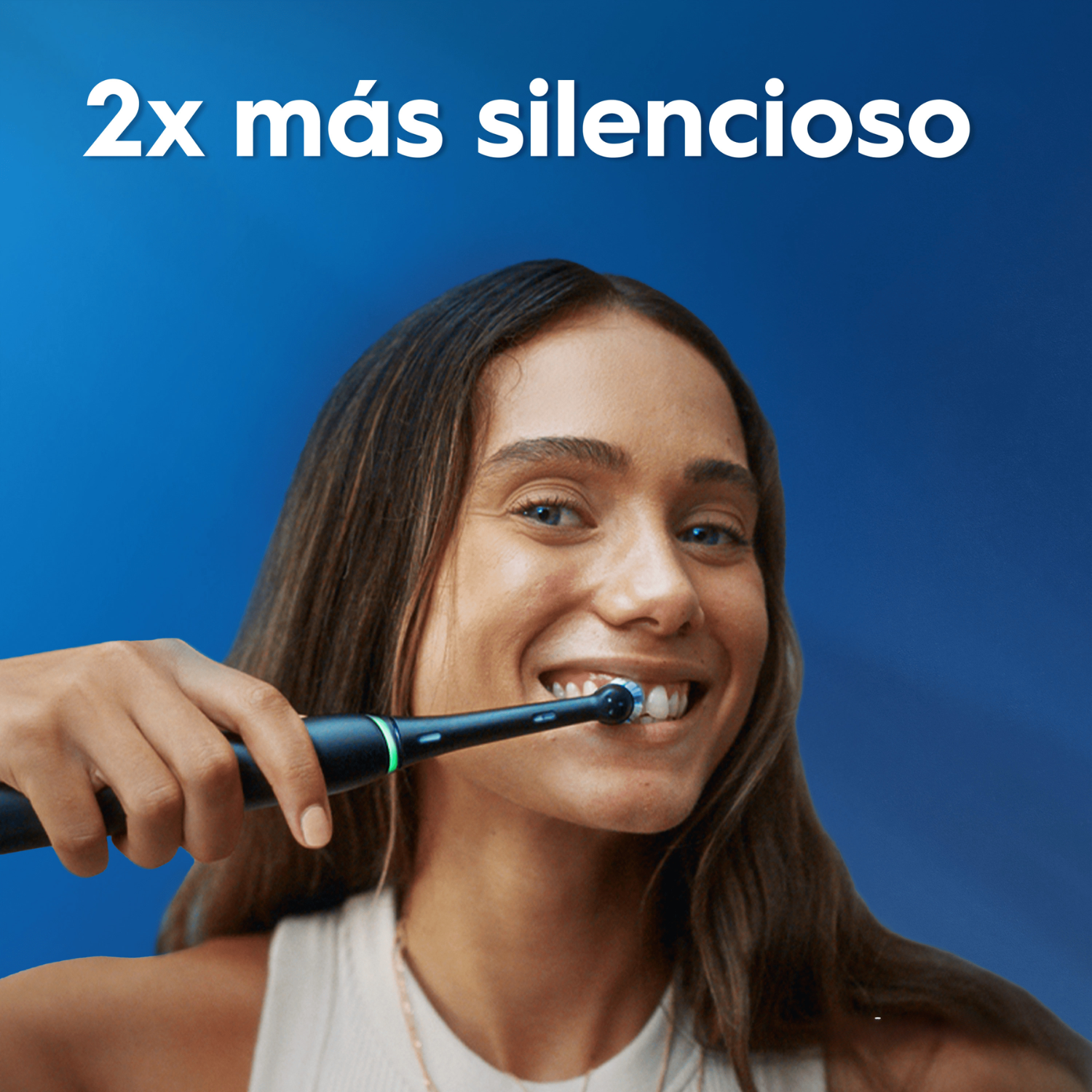 Una mujer sonriente se cepilla los dientes con un cepillo eléctrico negro sobre fondo azul.