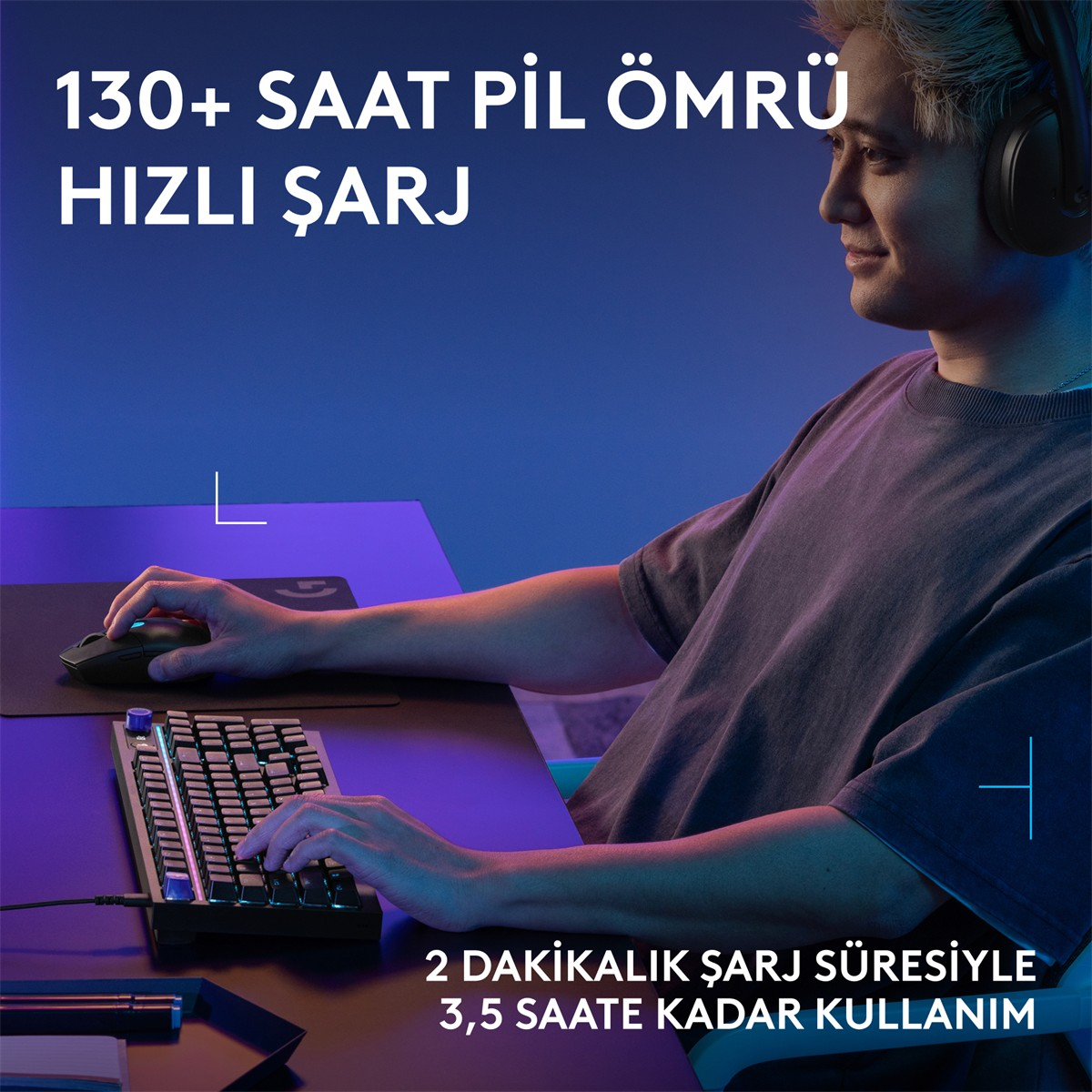 Kulaklıklı bir adam, mavi ışıklı bir odada oyun klavyesi ve fareden yararlanarak masa başında oturuyor.
