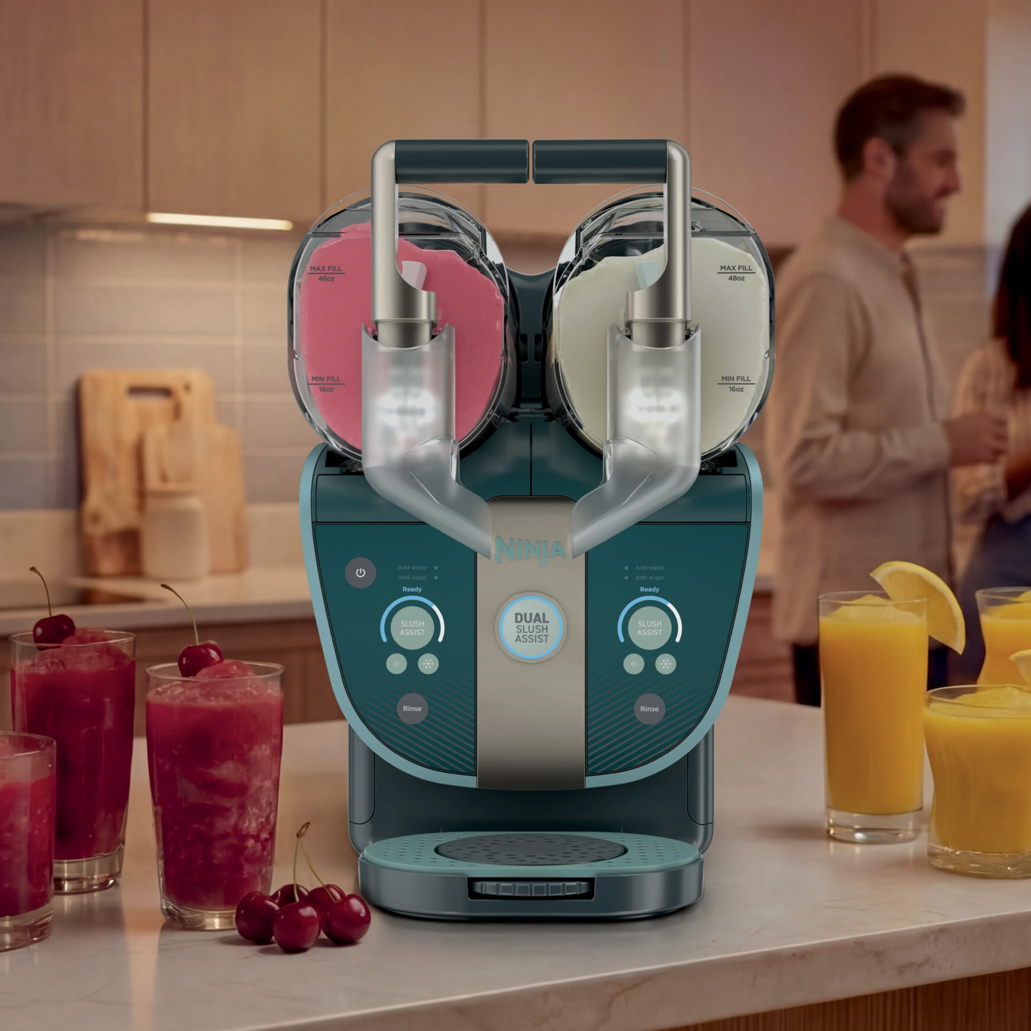 Eine türkisfarbene Ninja-Doppelslush-Maschine auf einer Küchentheke mit rosa und weißem Slush, umgeben von Getränken und Personen.