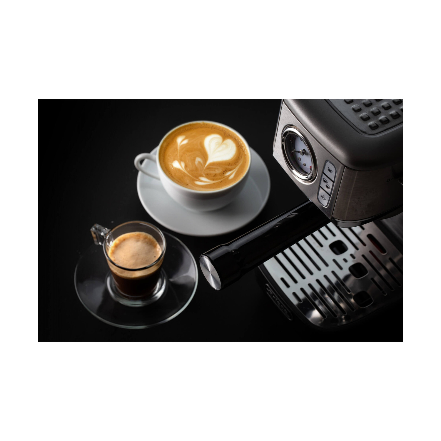 Una macchina da caffè con una tazza di cappuccino con cuore e un bicchiere di espresso su sfondo nero.