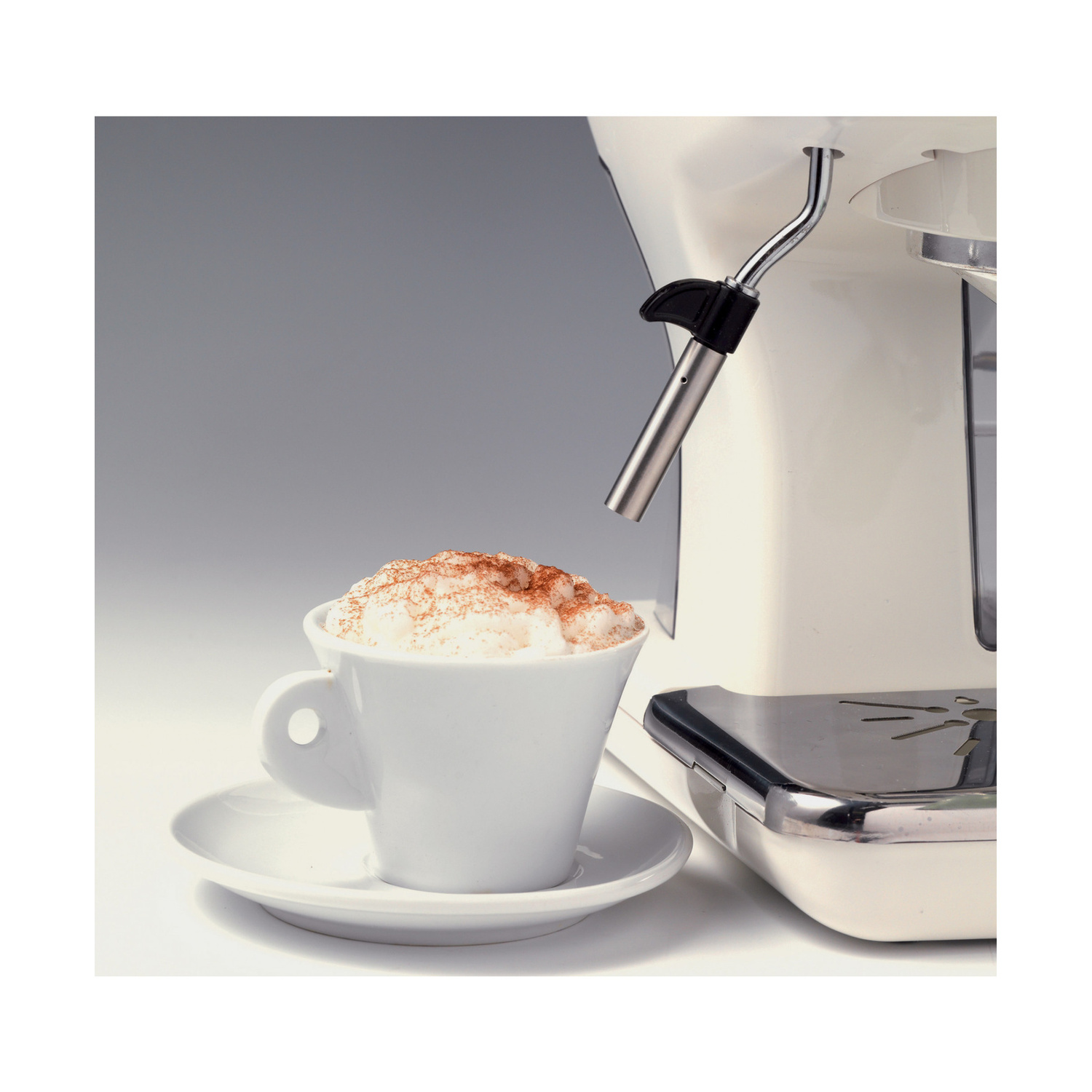 Una tazza bianca di cappuccino con schiuma e cacao è davanti a una macchina da caffè.