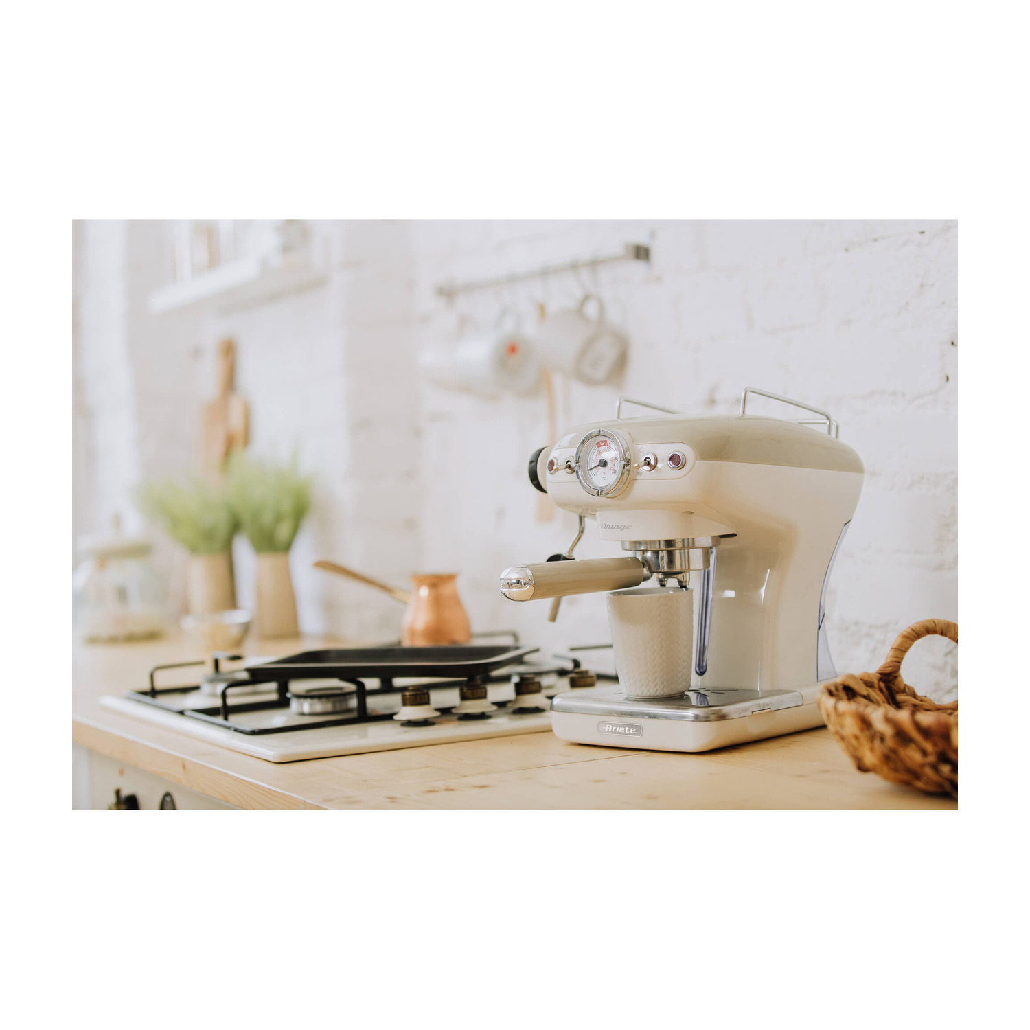 Una macchina da caffè espresso vintage beige su un bancone in legno vicino a un fornello.