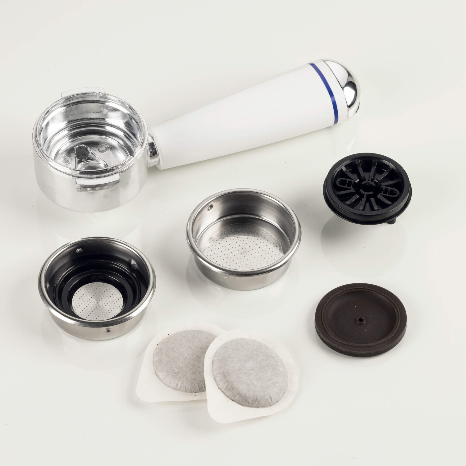 Portafiltro per macchina da espresso con filtri metallici smontati, guarnizioni e cialde di caffè su sfondo bianco.
