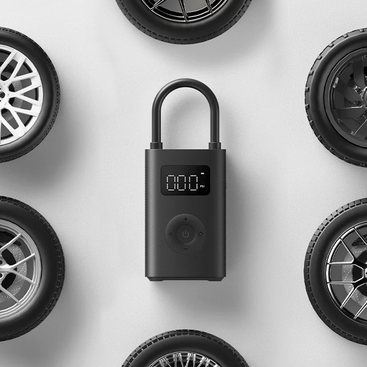Un compressore d'aria portatile nero al centro, circondato da cinque diverse ruote d'auto su sfondo chiaro.