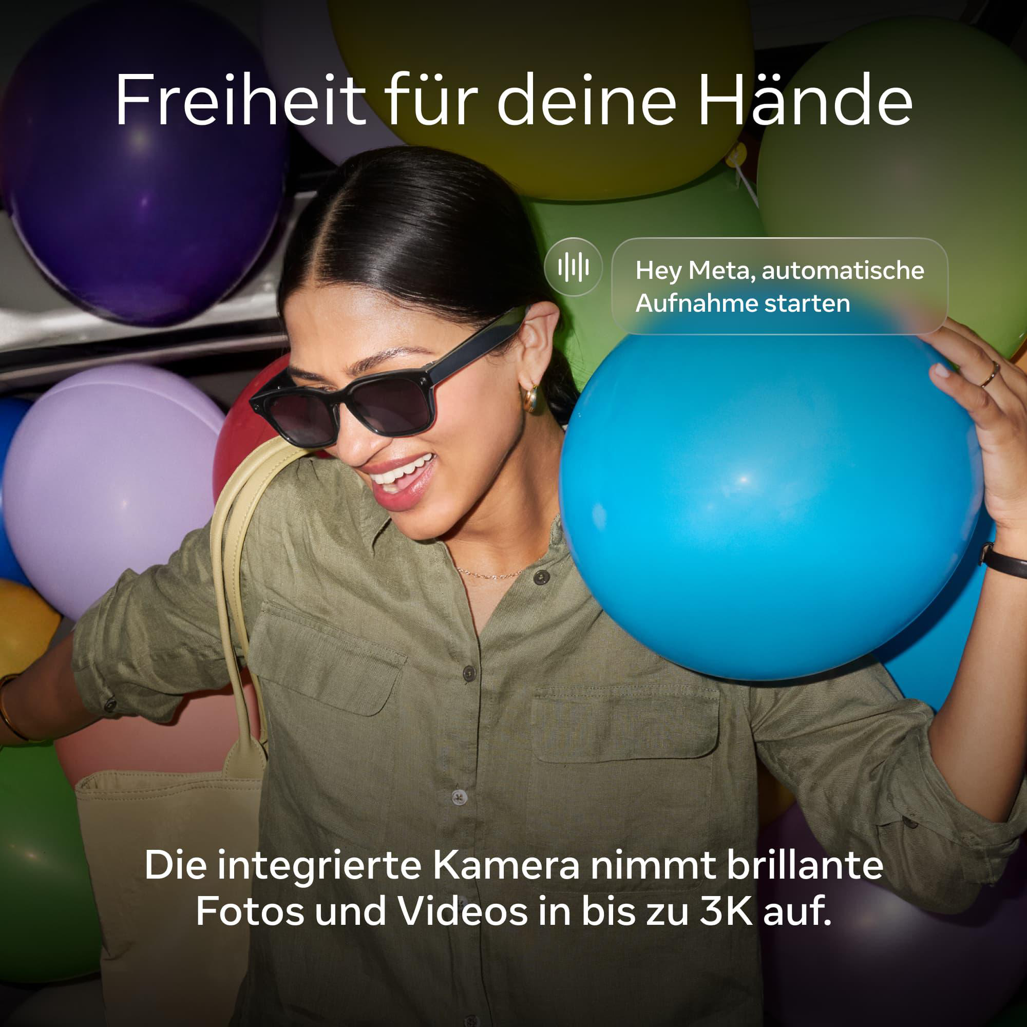 Eine Frau mit Sonnenbrille und grünem Hemd hält einen blauen Ballon umgeben von bunten Luftballons.