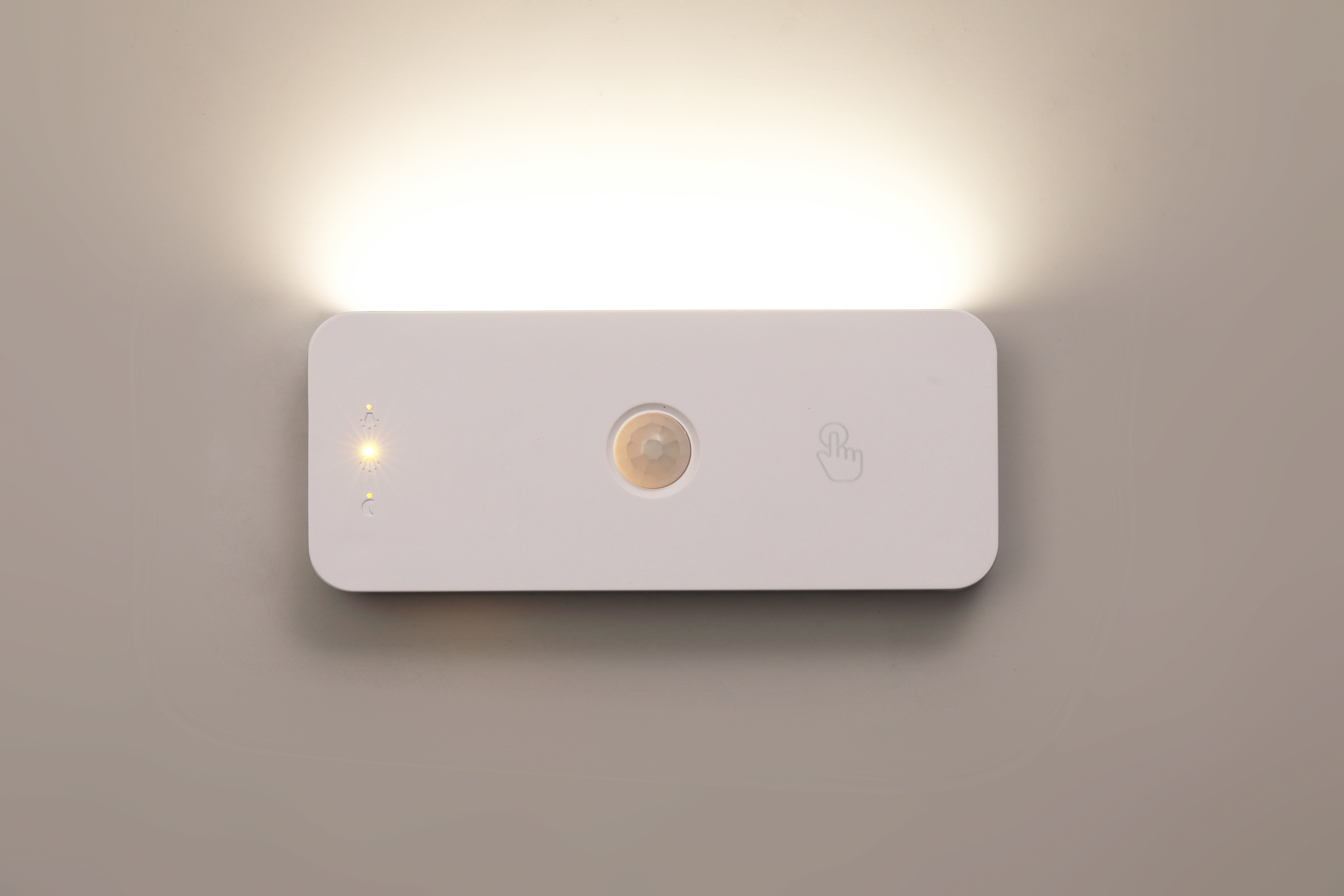 Eine weiße, wandmontierte LED-Leuchte mit Bewegungsmelder leuchtet an der Wand.