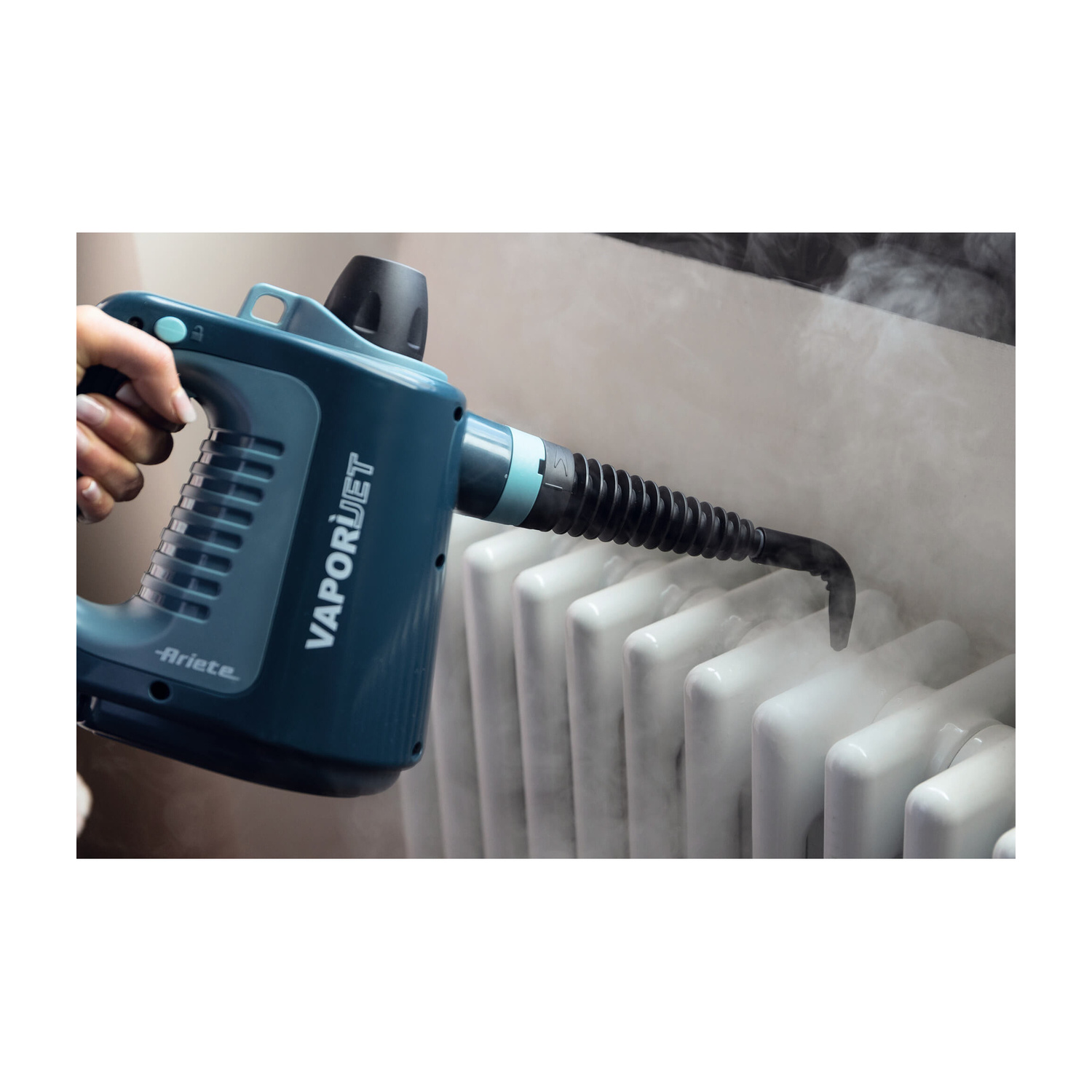 Un pulitore a vapore portatile blu pulisce un termosifone bianco, emettendo vapore.