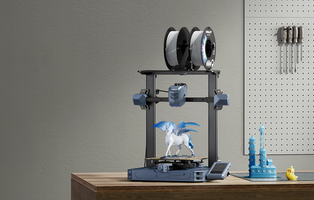 Egy 3D nyomtató egy fa asztalon egy pegazus figurát nyomtat, felül orsókkal, háttérben szerszámokkal.
