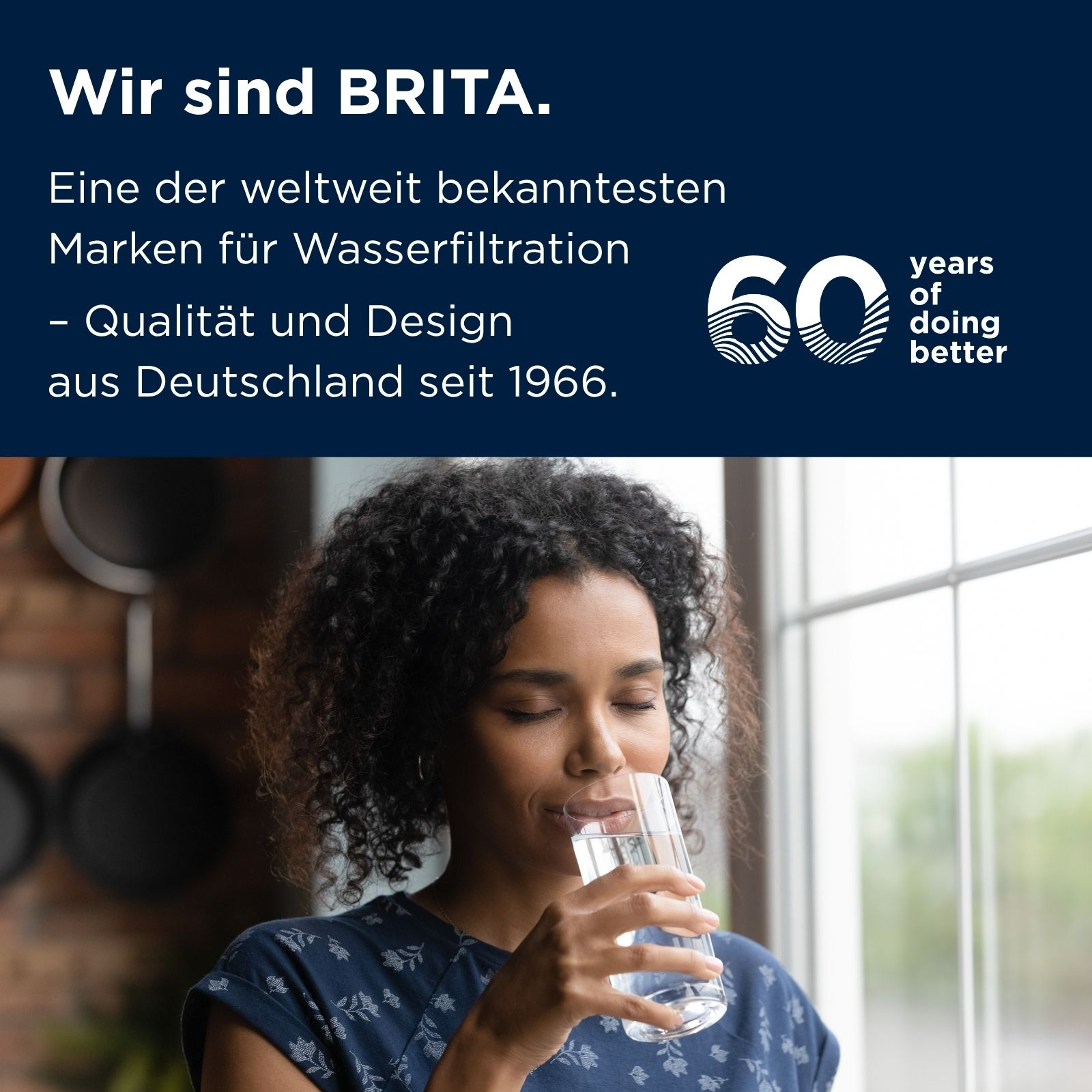 Eine lächelnde Frau mit dunklen Locken trinkt frisches Wasser aus einem Glas.