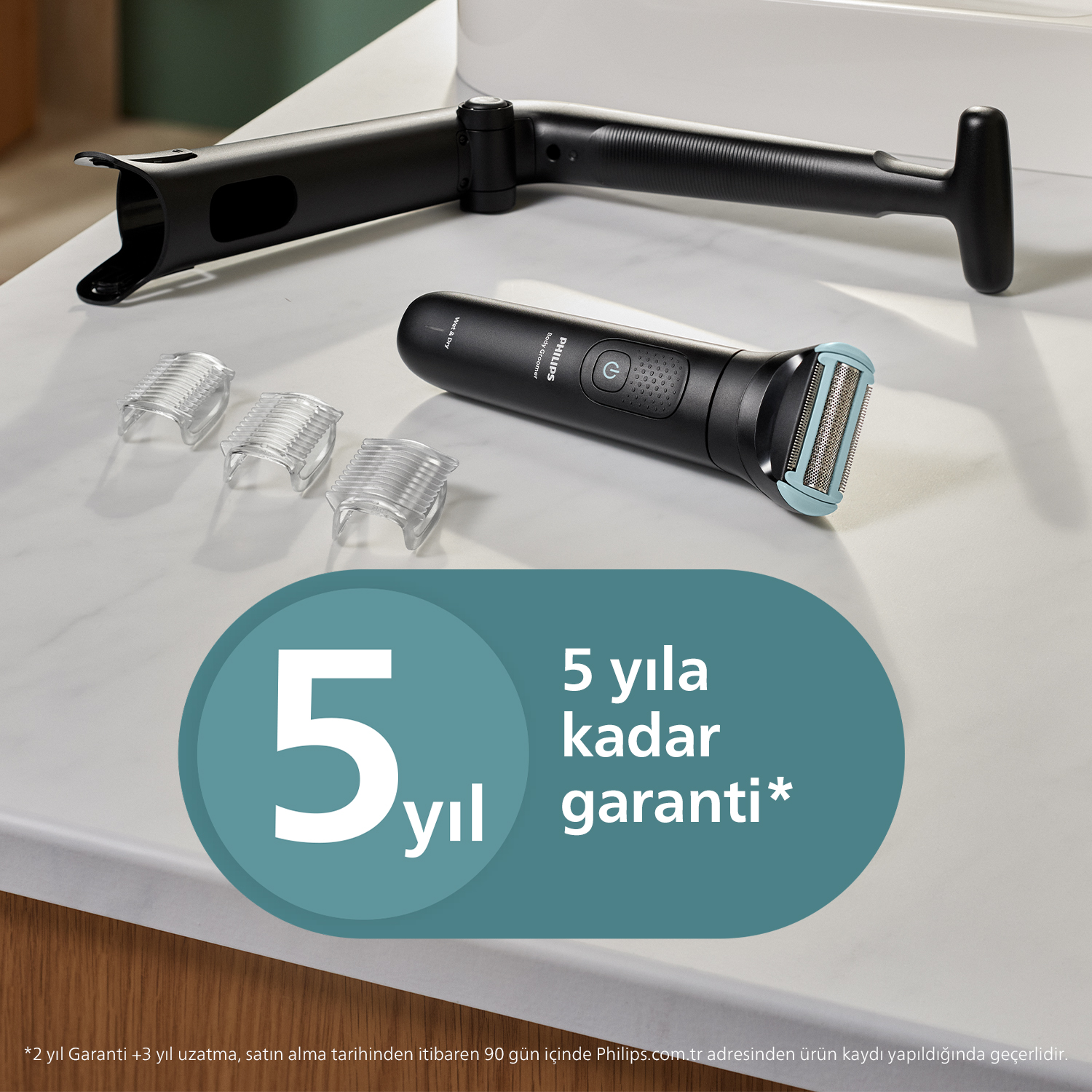 Üç tarak ve uzatma koluna sahip Philips vücut bakım tıraş makinesi, beyaz tezgah üzerinde 5 yıl garanti ibaresiyle.