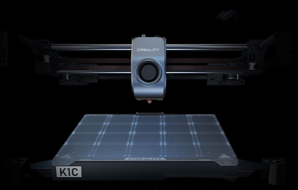 Creality K1C 3D nyomtató szürke extruder fejjel és világító nyomtatási felülettel fekete háttér előtt.