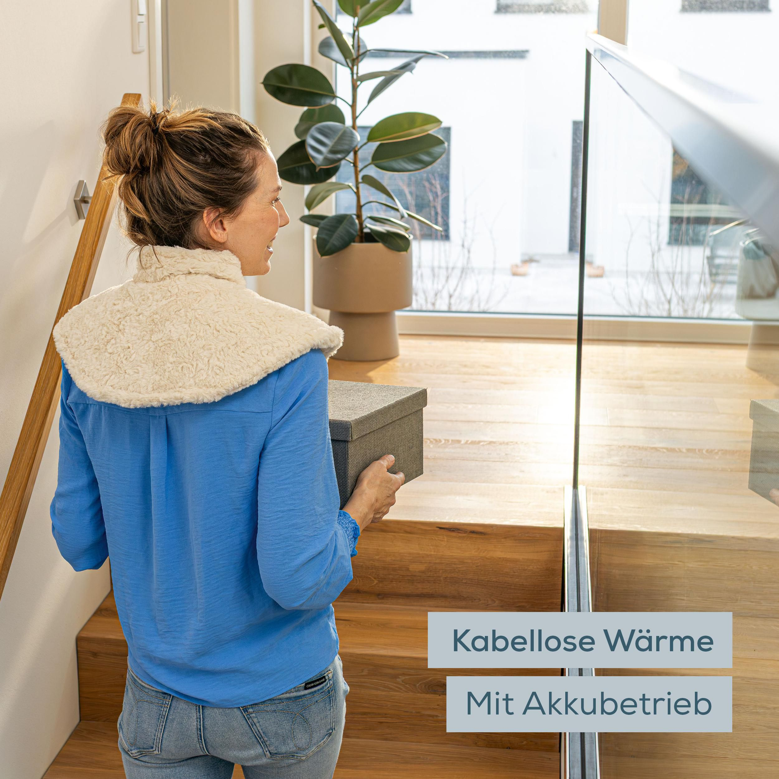 Eine Frau in blauem Hemd und mit Heizkragen geht eine Holztreppe hoch und hält eine Box.