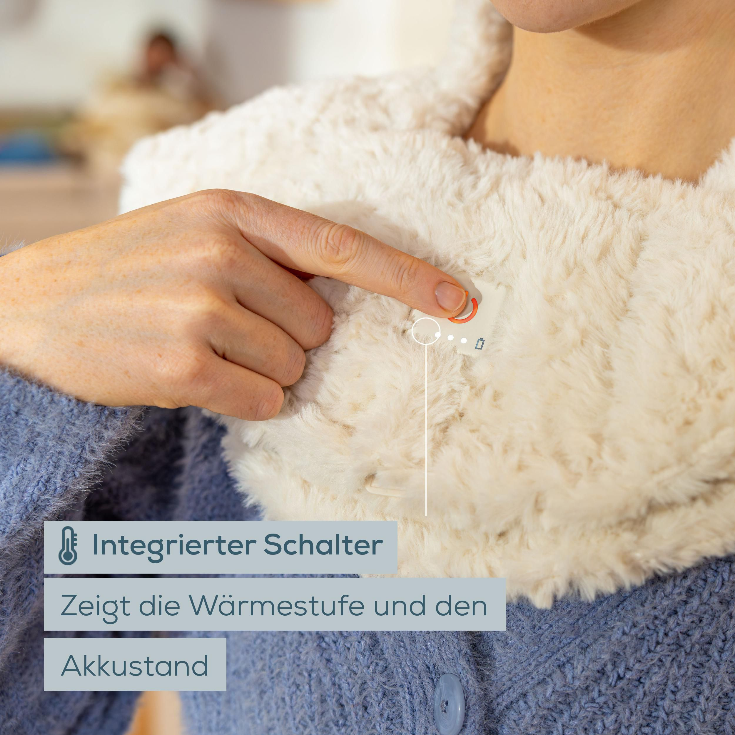 Finger drückt auf Schalter eines flauschigen, beigen Wärmekragens über blauem Pullover.