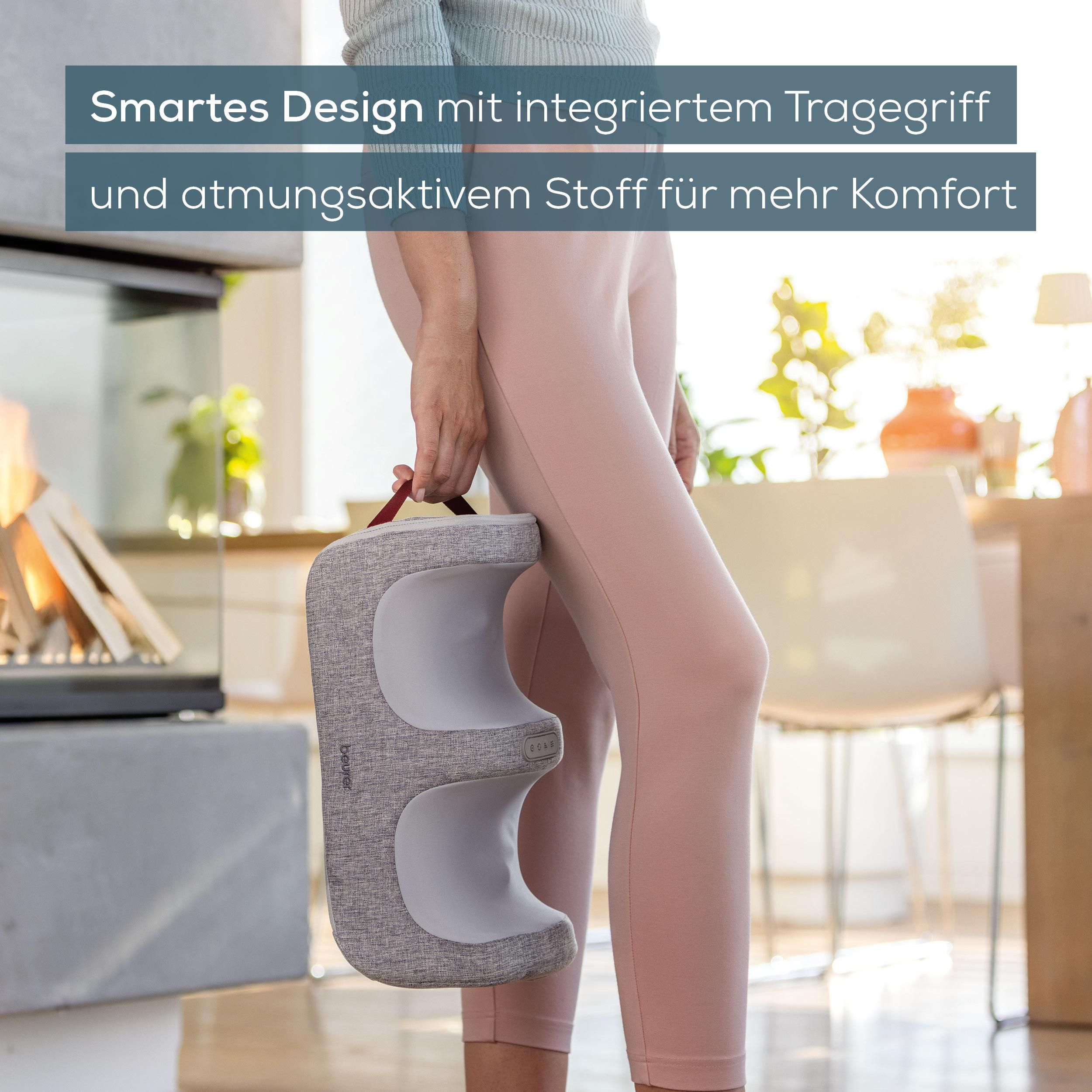 Person hält ein graues Massagekissen mit rotem Griff in einem hellen Raum.