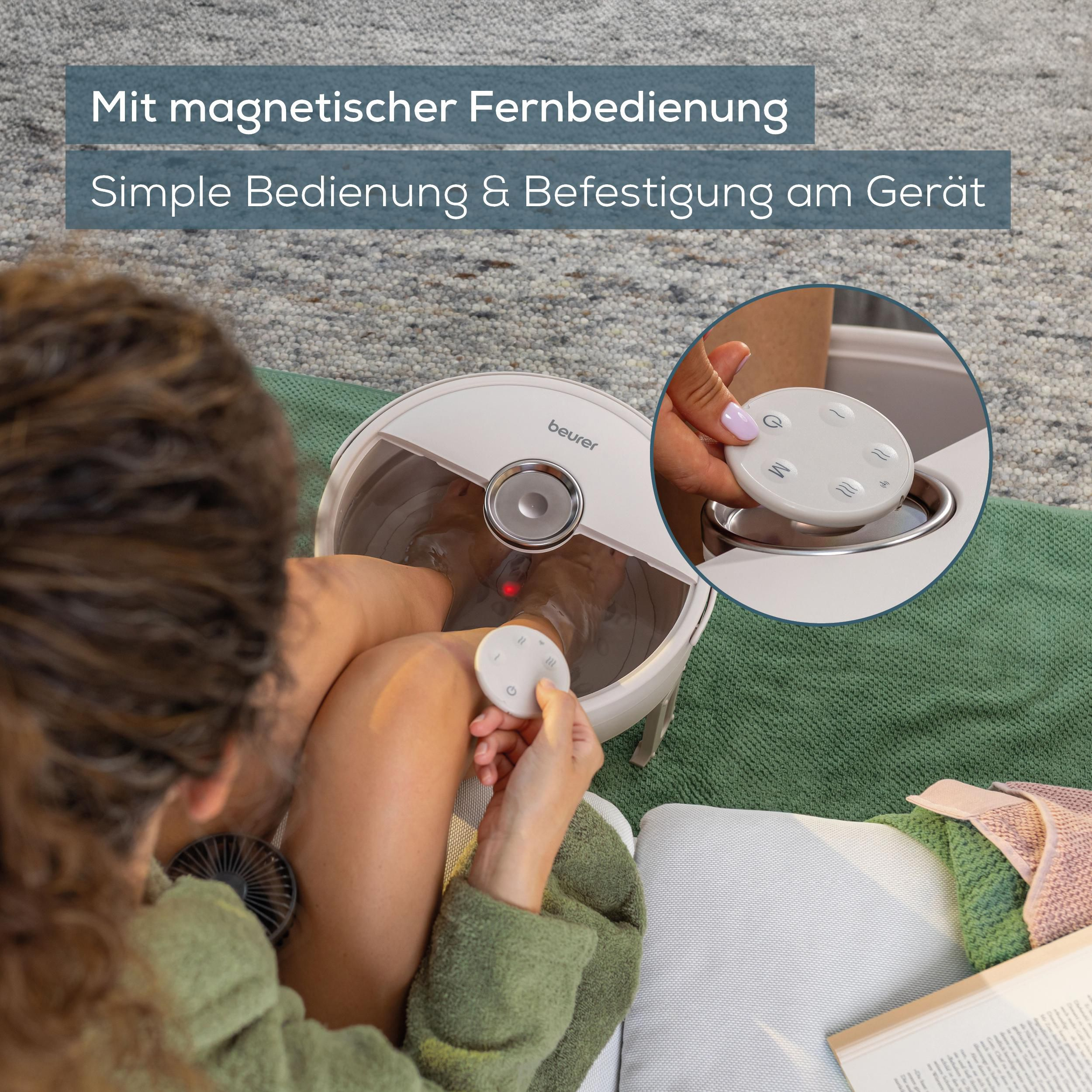 Eine Person nutzt eine magnetische Fernbedienung für ein Beurer Fußbad auf einer grünen Matte, mit Detailansicht.