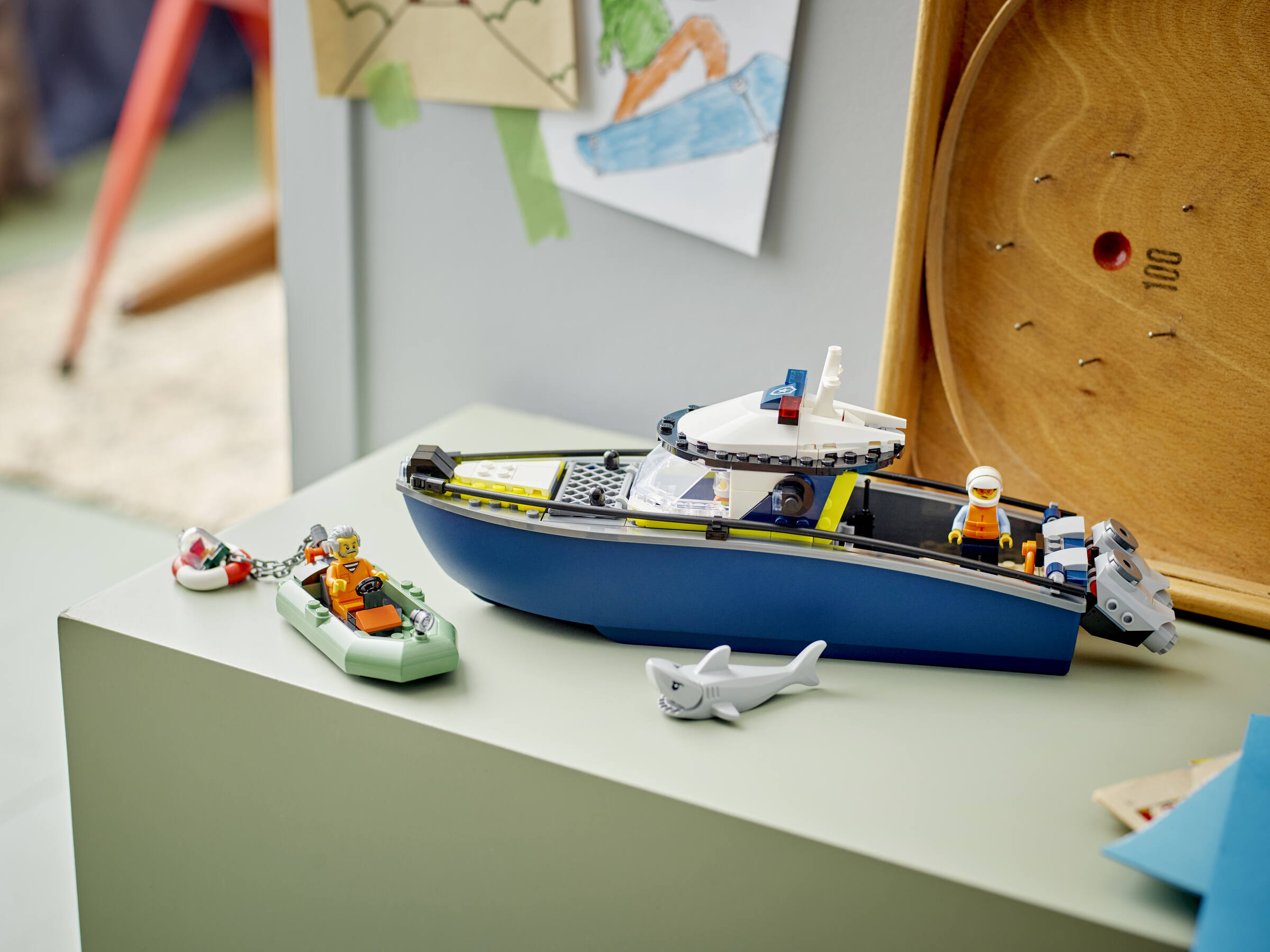 Lego Polizeiboot und ein kleineres Boot auf einer hellgrünen Oberfläche mit einer Hai-Figur.