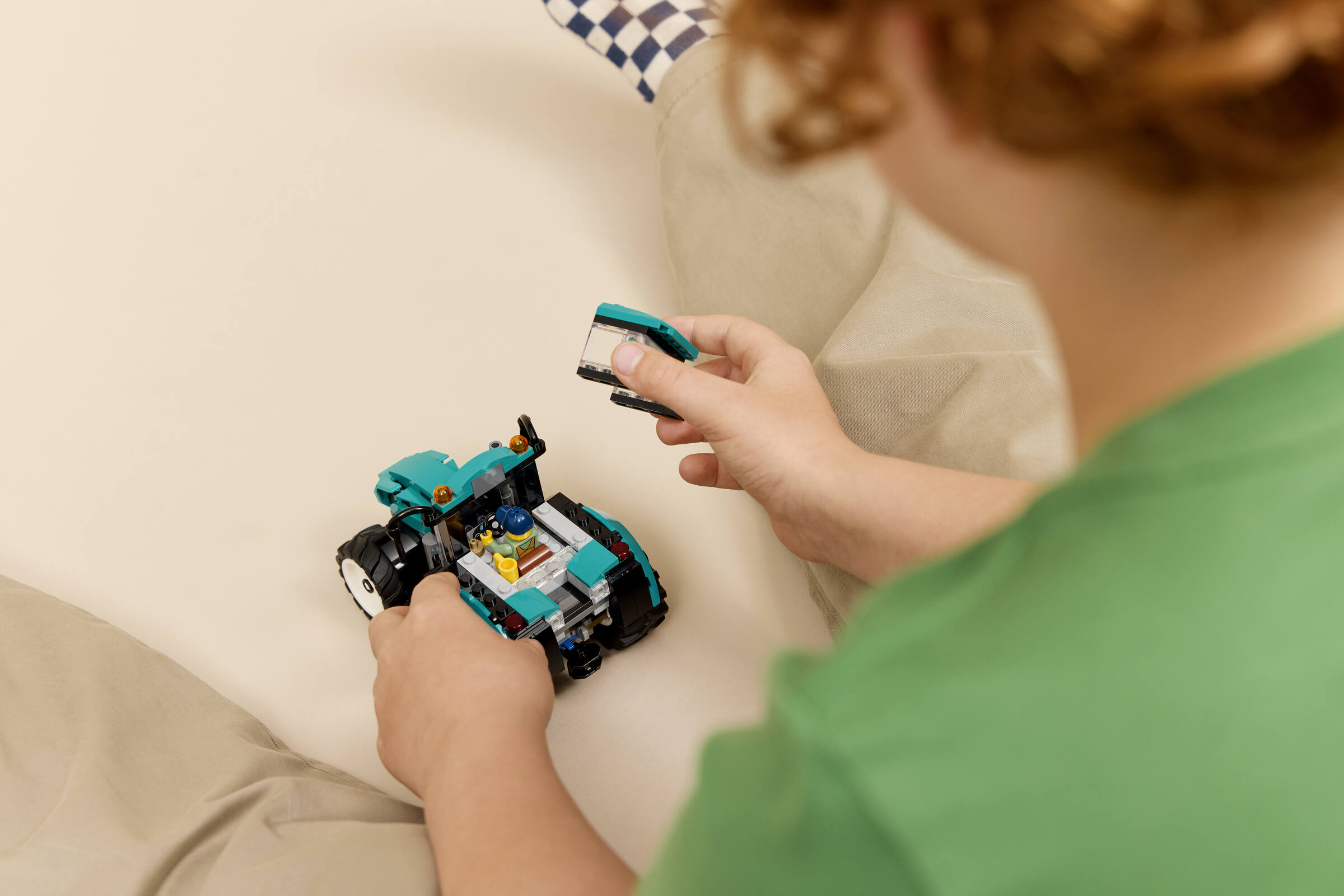 Un enfant assemble un tracteur jouet bleu avec des blocs de construction.