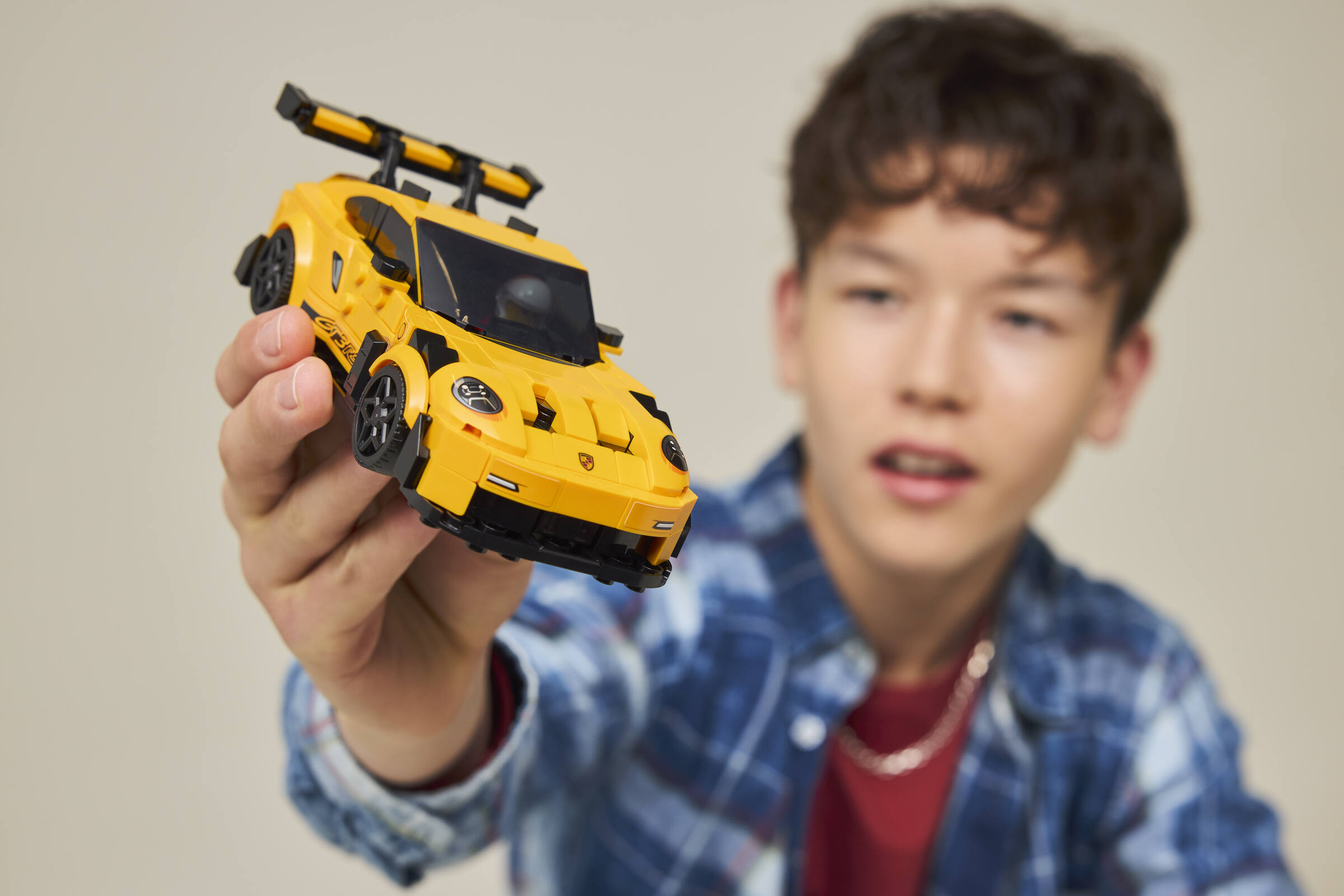 Un ragazzo mostra con orgoglio un'auto giocattolo Lego gialla alla telecamera.