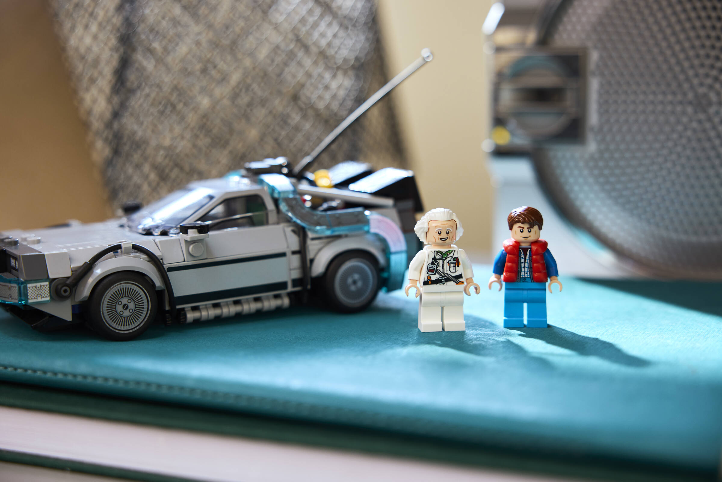 Lego Back to the Future DeLorean mit Minifiguren Doc Brown und Marty McFly auf einer blauen Oberfläche.
