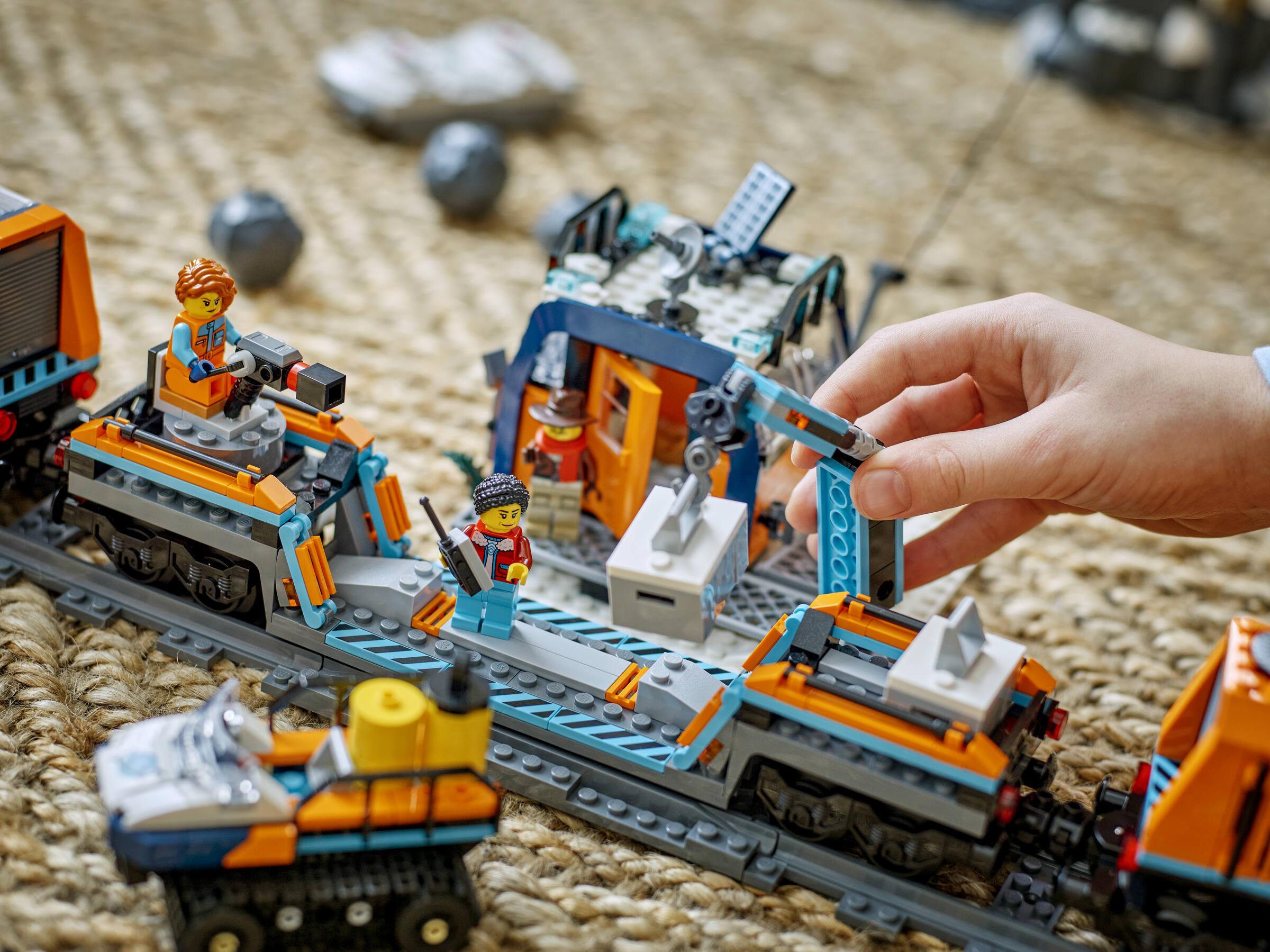 Un enfant construit des trains spatiaux Lego et une base avec des grues sur un tapis.