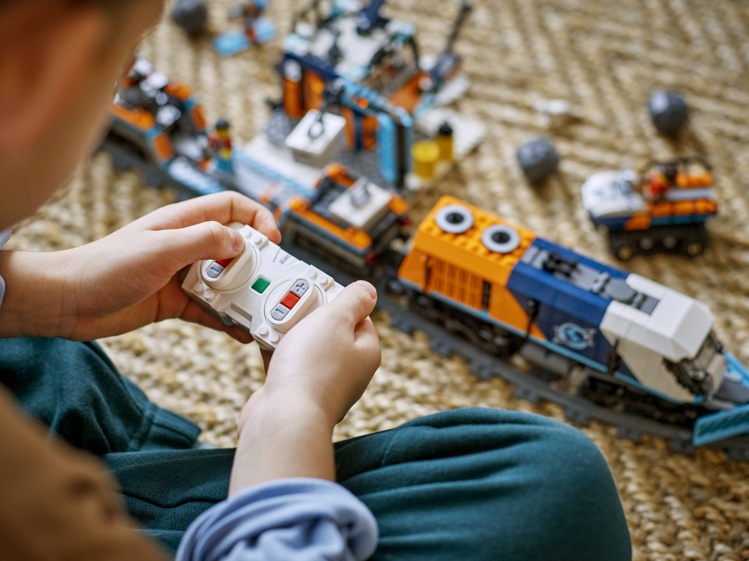 Un enfant utilise une télécommande pour faire fonctionner un train jouet sur un tapis.