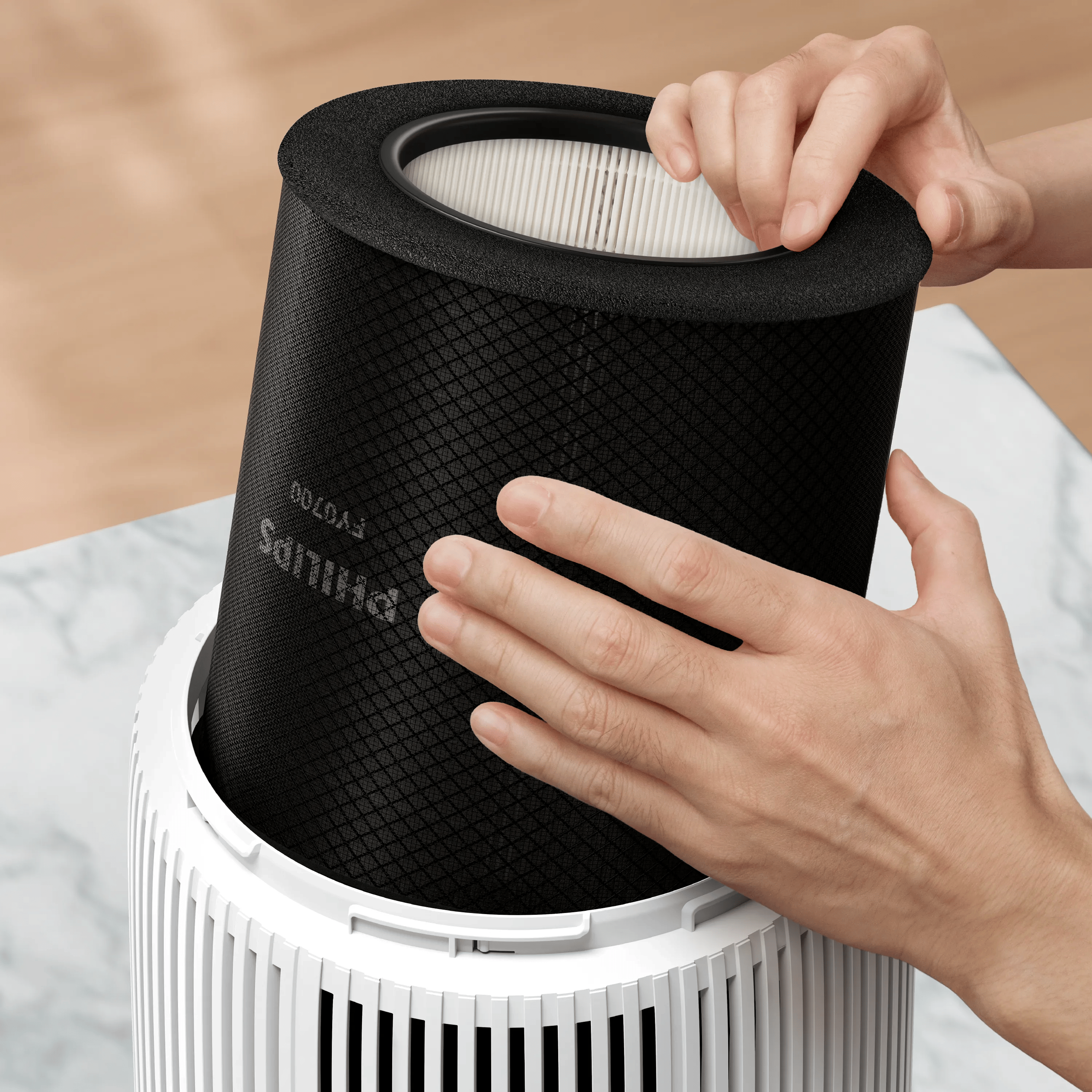 Hände setzen einen schwarzen Philips-Filter in ein weißes Luftreinigergehäuse ein.