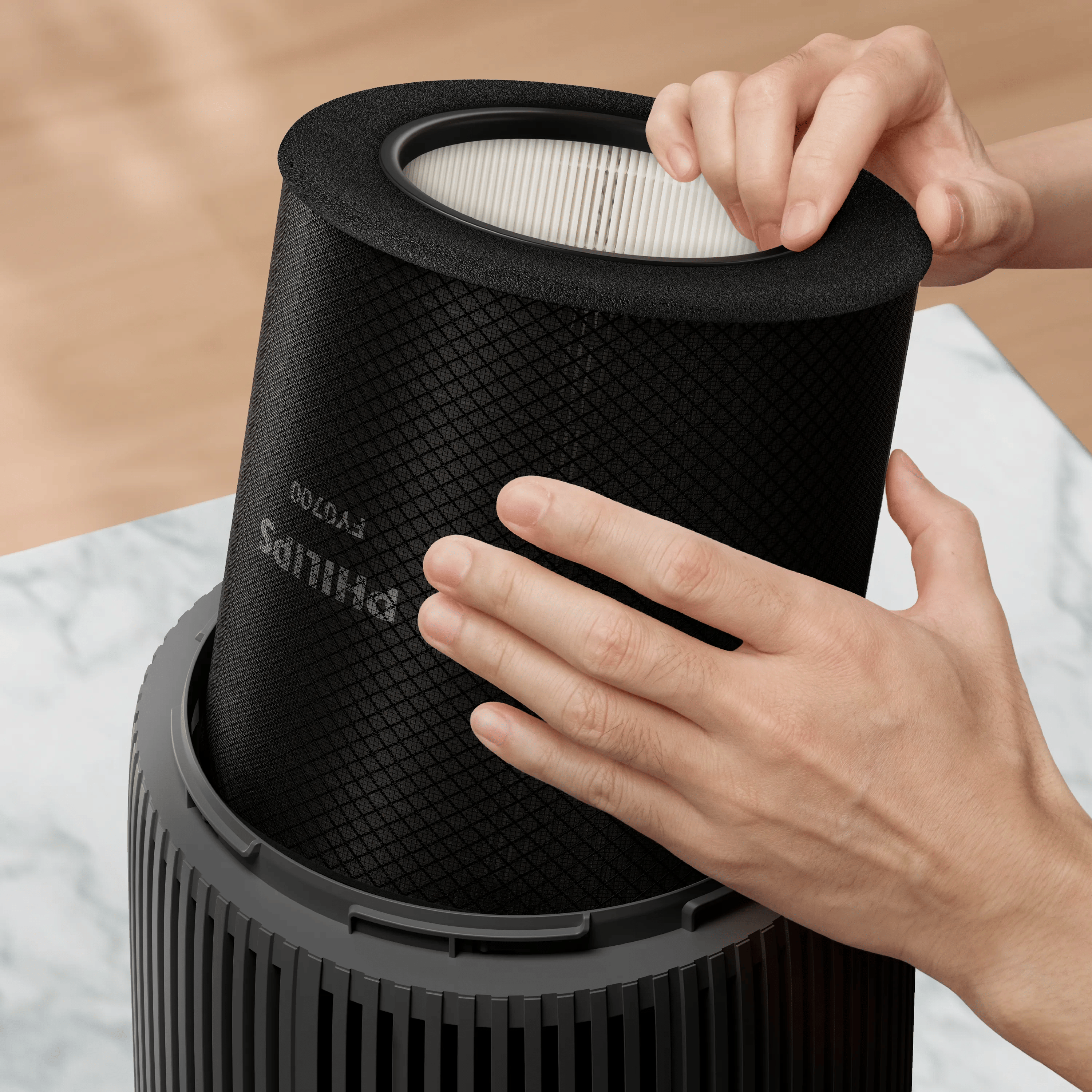 Hände setzen einen zylindrischen schwarzen Philips Luftreinigerfilter in das Gerät ein.