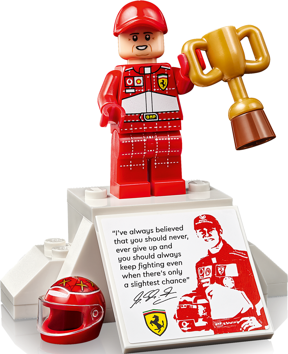 Ferrari-Rennfahrer-Legofigur mit Pokal und Zitat von Michael Schumacher auf einem weißen Sockel.