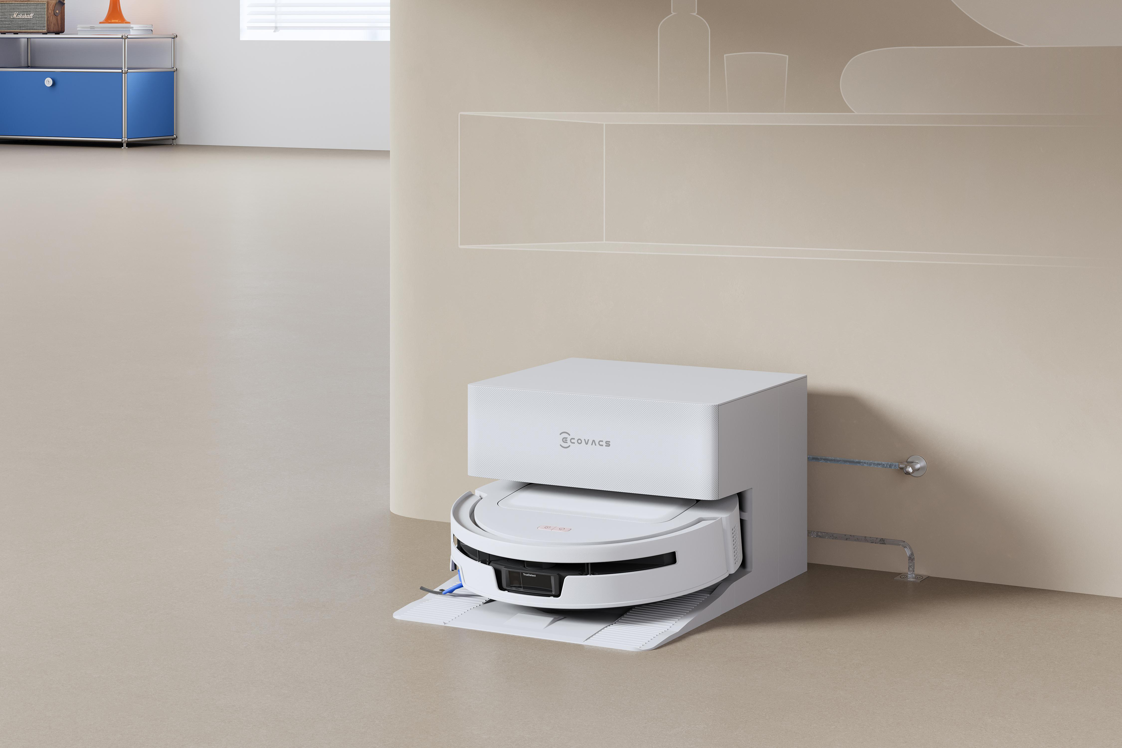 Ein weißer Ecovacs Saugroboter in seiner Ladestation in einem modern eingerichteten, beige gehaltenen Raum.