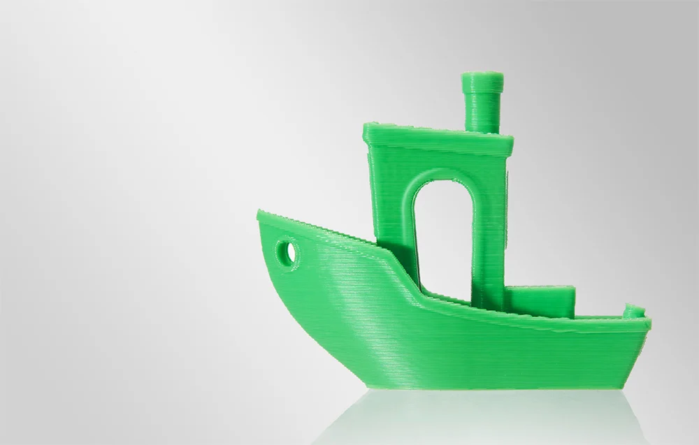 Egy zöld, 3D-nyomtatott kishajó modell világos háttér előtt.