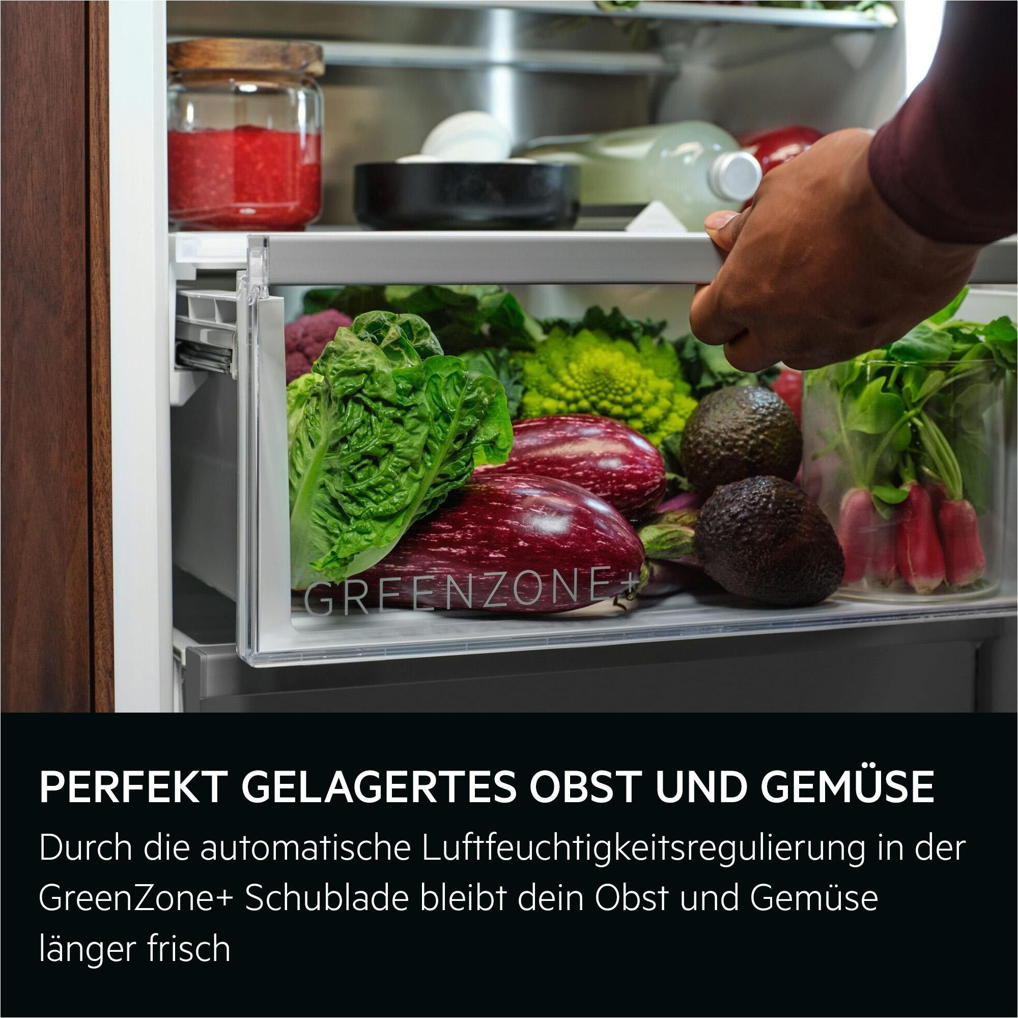 Eine Hand öffnet die GreenZone+ Schublade eines Kühlschranks mit frischem Obst und Gemüse.