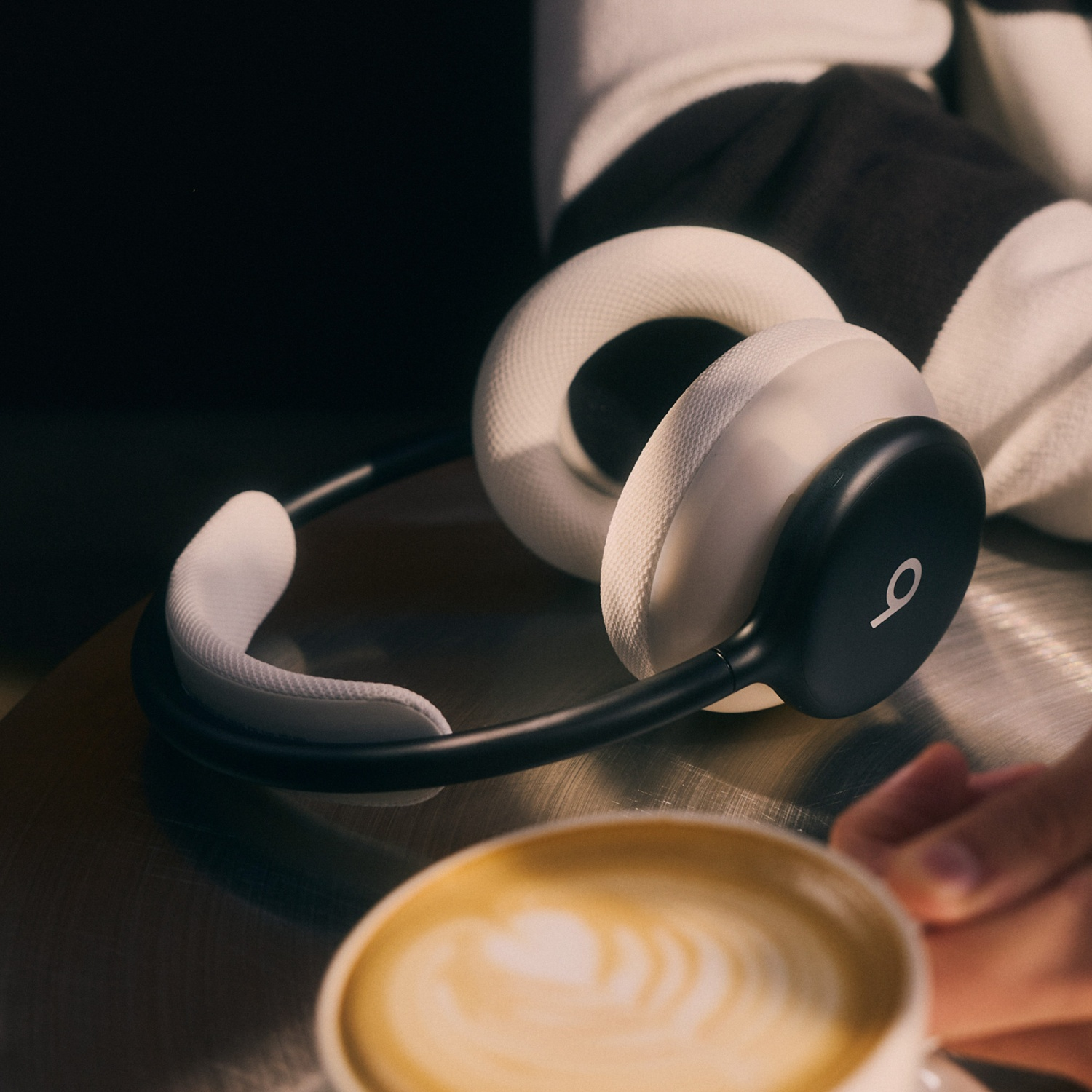 Casque blanc et noir sur une table à côté d'une tasse de café avec latte art.