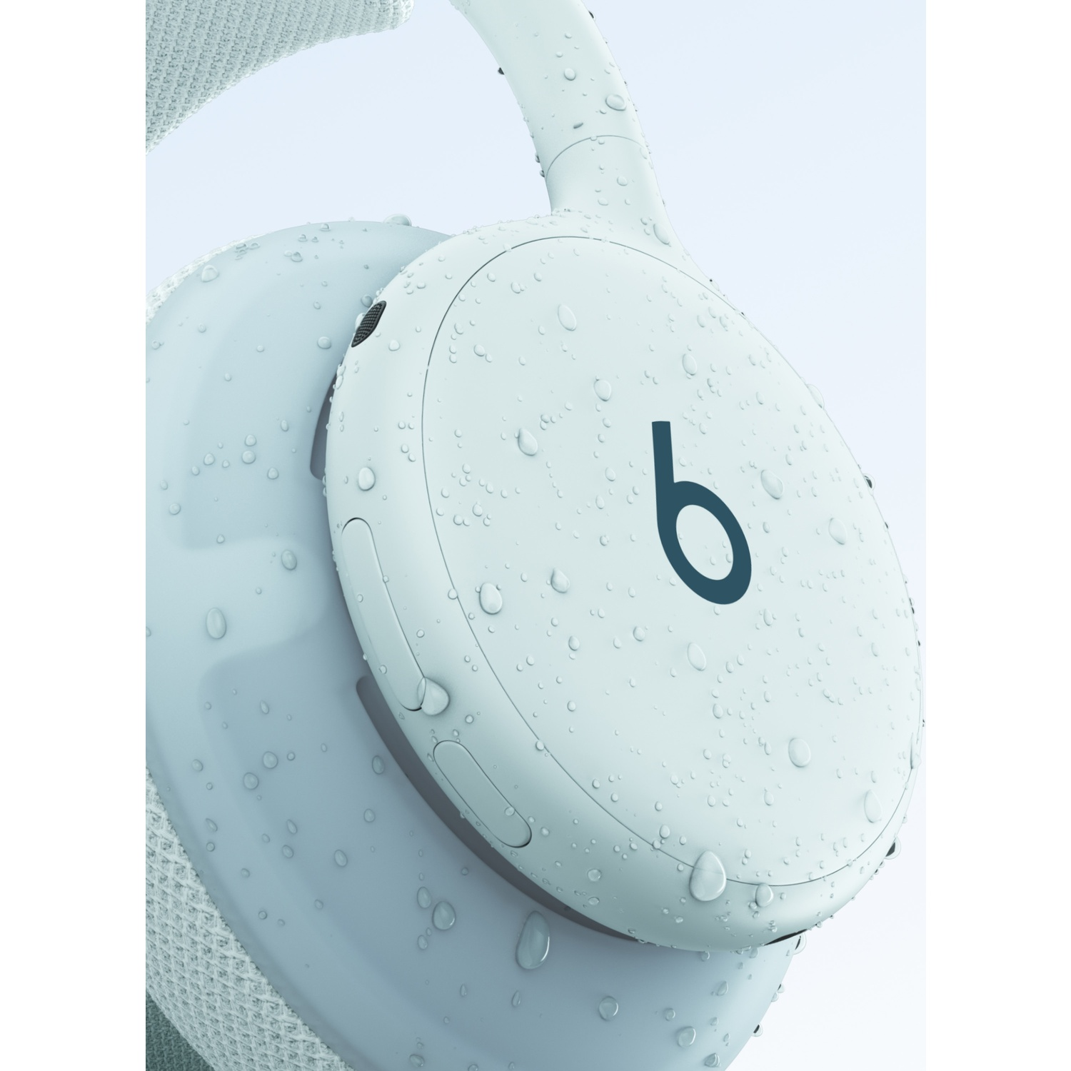 Gros plan d'un casque Beats bleu clair couvert de gouttes d'eau sur fond clair.