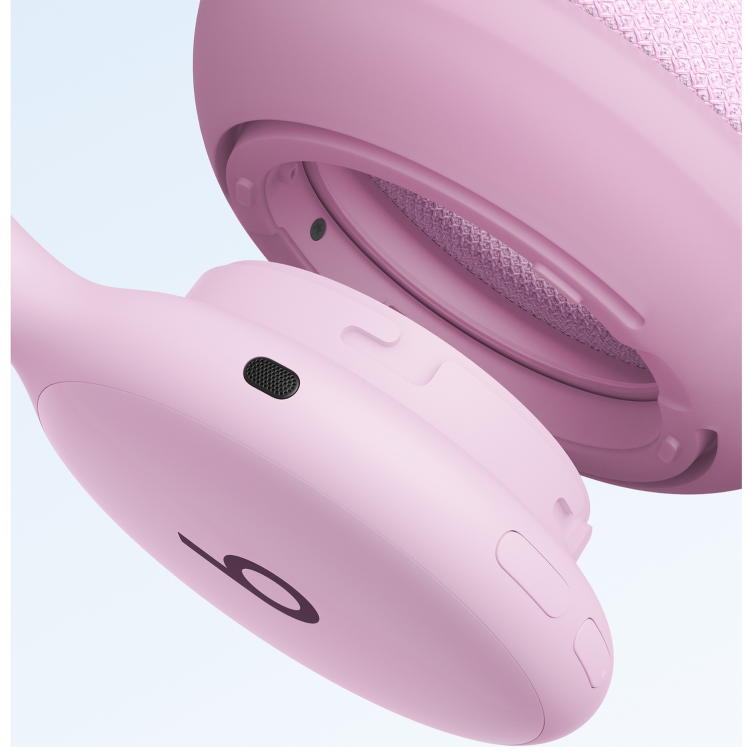 Gros plan d'un casque sans fil rose montrant un coussinet d'oreille détaché sur fond clair.
