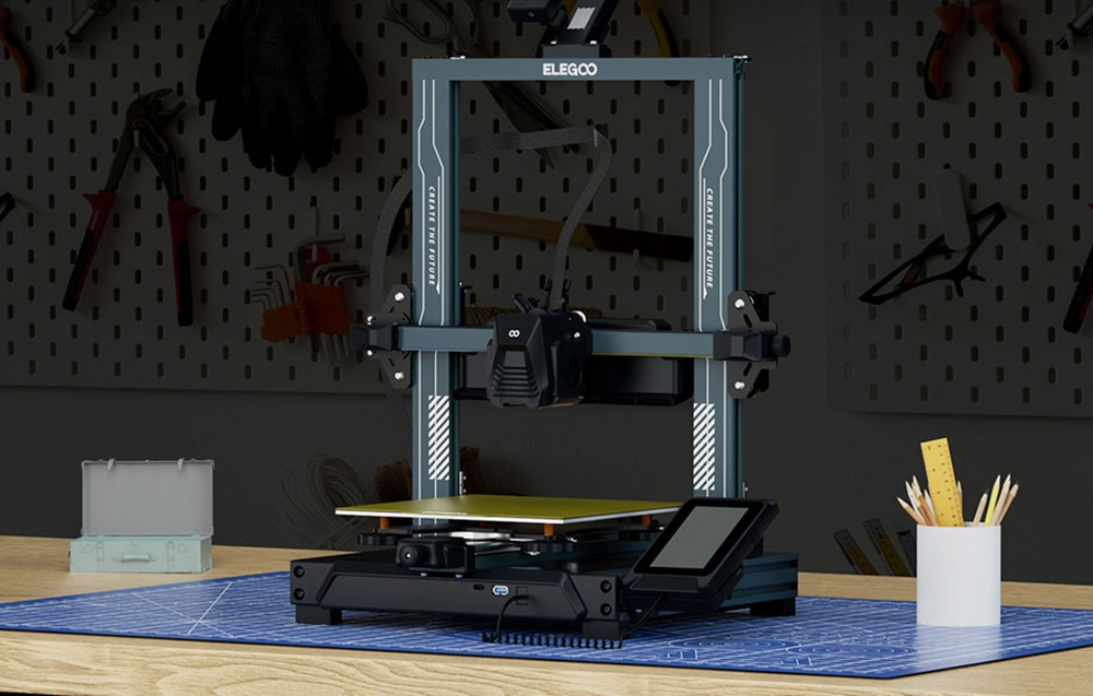 ELEGOO 3D nyomtató kék szőnyegen, szerszámos hátfal előtt.