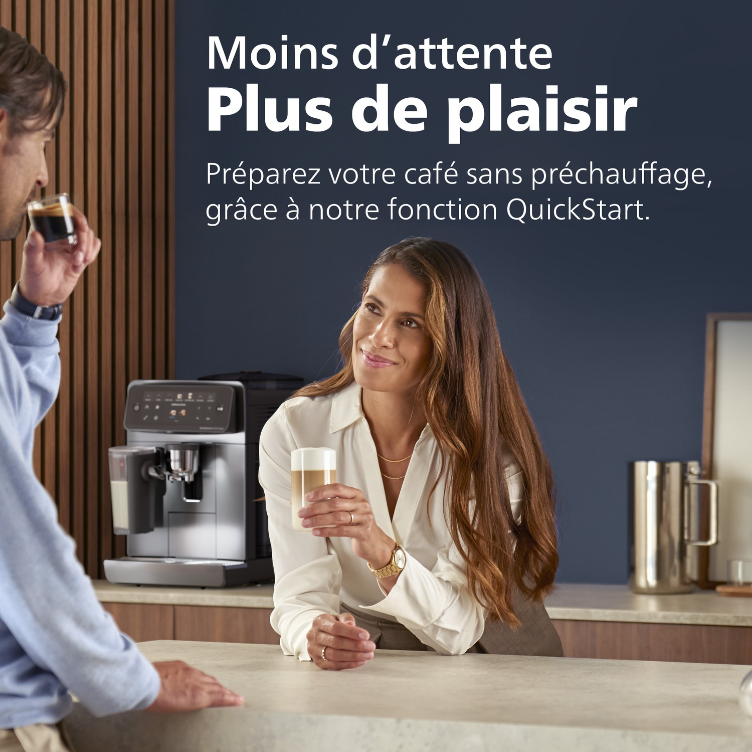 Une femme tient un latte pendant qu'un homme boit de l'espresso, avec une machine à café en arrière-plan.