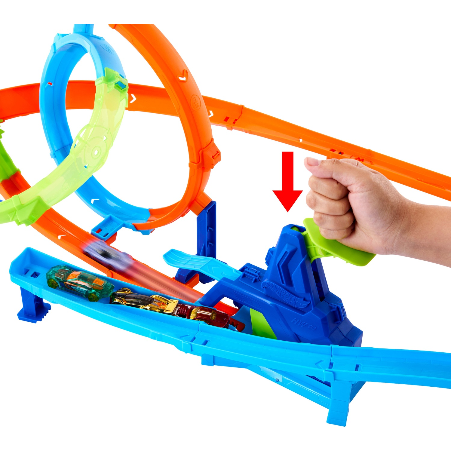 A hand presses down a blue launcher on a colorful Hot Wheels toy racetrack featuring loops.