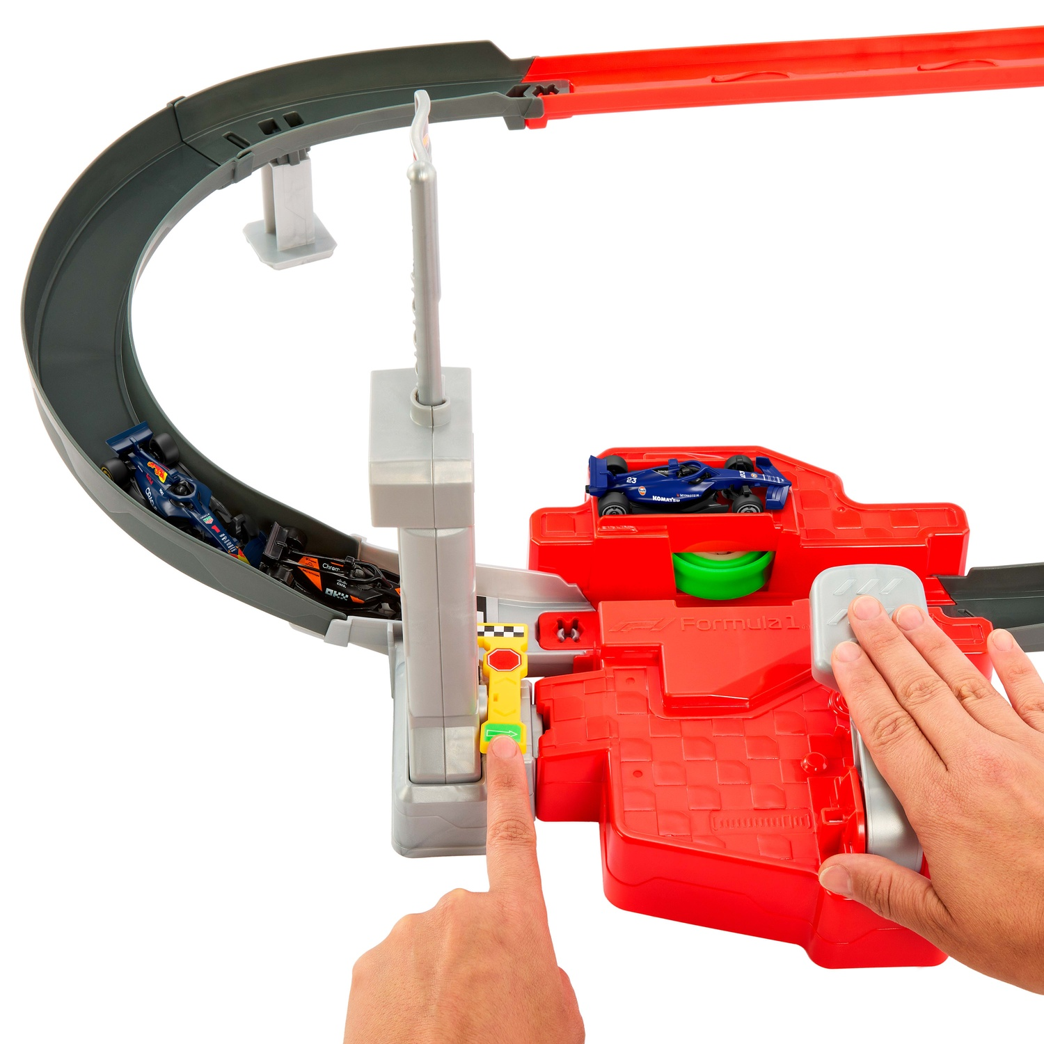 A toy racing set with a red track, Formula 1 cars, and hands pressing the launcher pad.