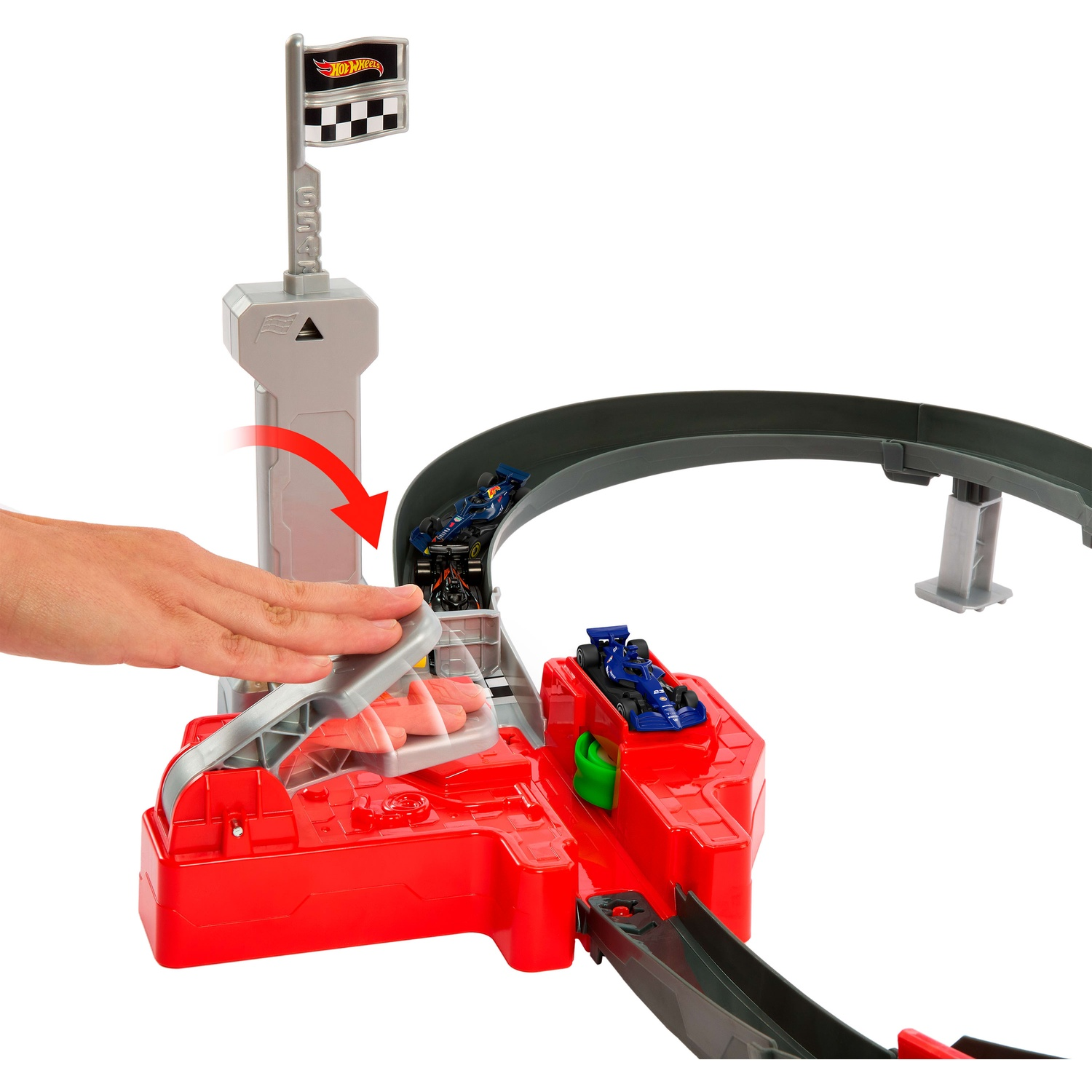 A hand interacts with a red and grey Hot Wheels toy race track with blue cars and a finish line flag.