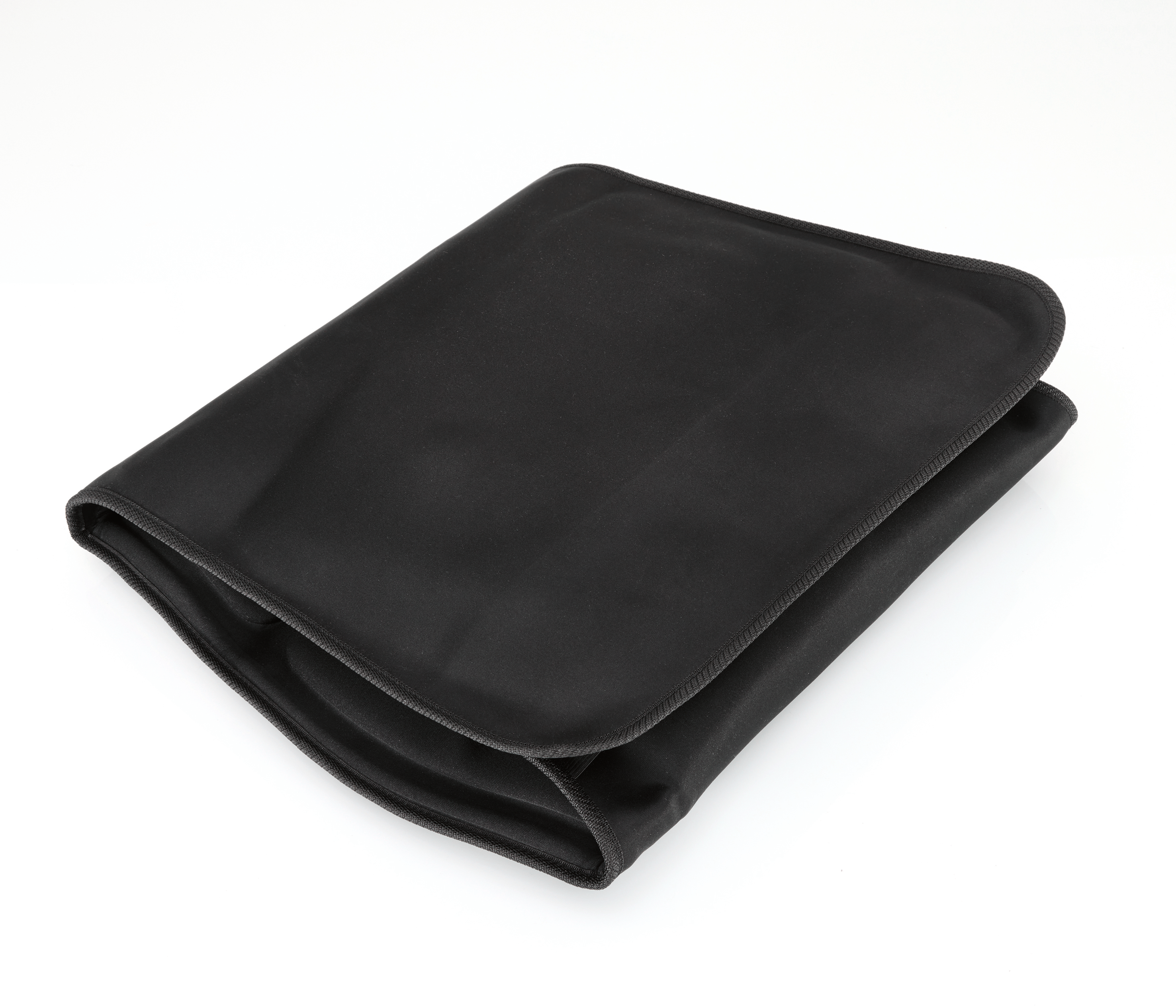 Eine schwarze, gefaltete Stofftasche liegt auf einer weißen Oberfläche.