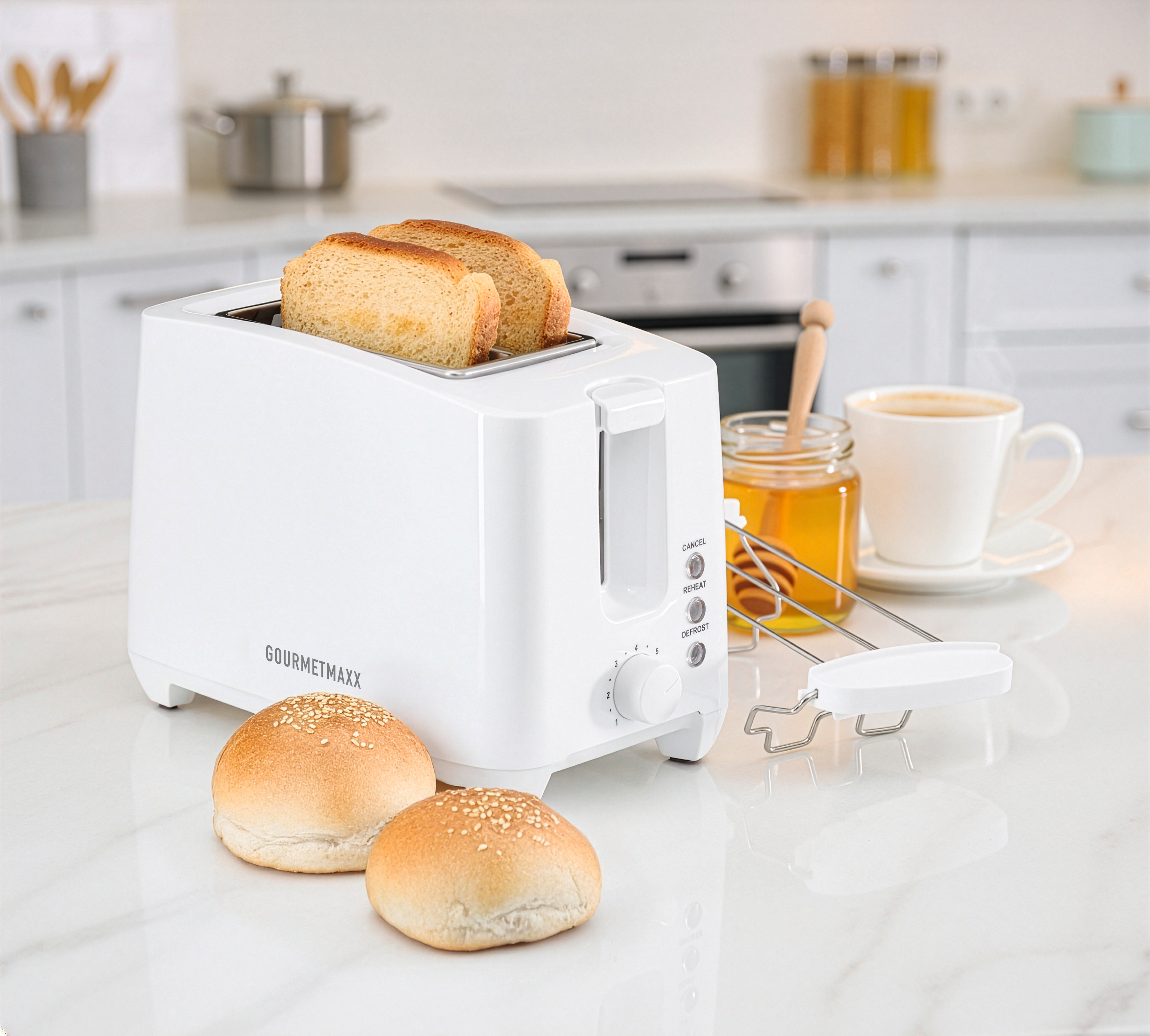 Ein weißer Toaster mit zwei Brotscheiben, zwei Brötchen, einem Honigglas und einer Tasse Kaffee auf der Küchenzeile.